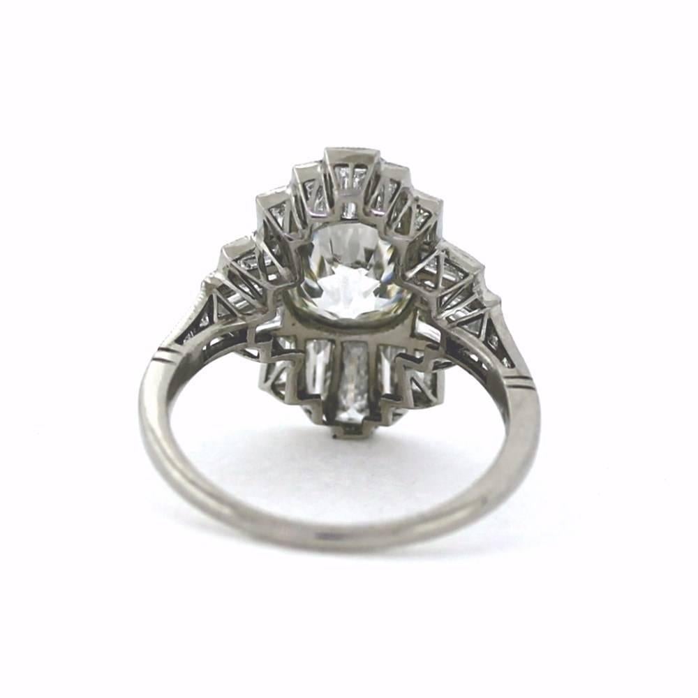 This super sweet geometric ring has tapered baguettes surrounding an 1.84ct Antique cushion cut white diamond with 3 european cut diamonds down each shank.  Milgrain on top and hand bladed engravings underneath.  Size able size 7.