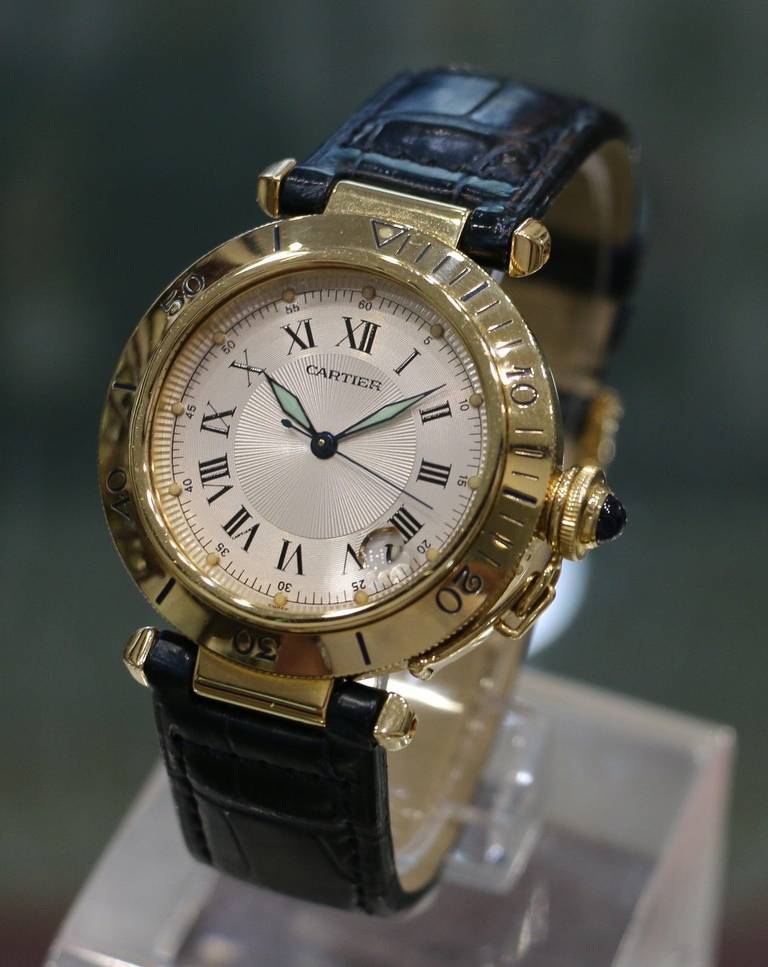 Brand:	Cartier
Style Number:	1020
Series:	Pasha
Case Material:	18K Yellow Gold
Dial: 	Silvered Guilloche
Movement:	Automatic
Functions: 	Hours, Minutes, Seconds, Date
Crystal Material:	Scratch Resistant Sapphire
Case Diameter: