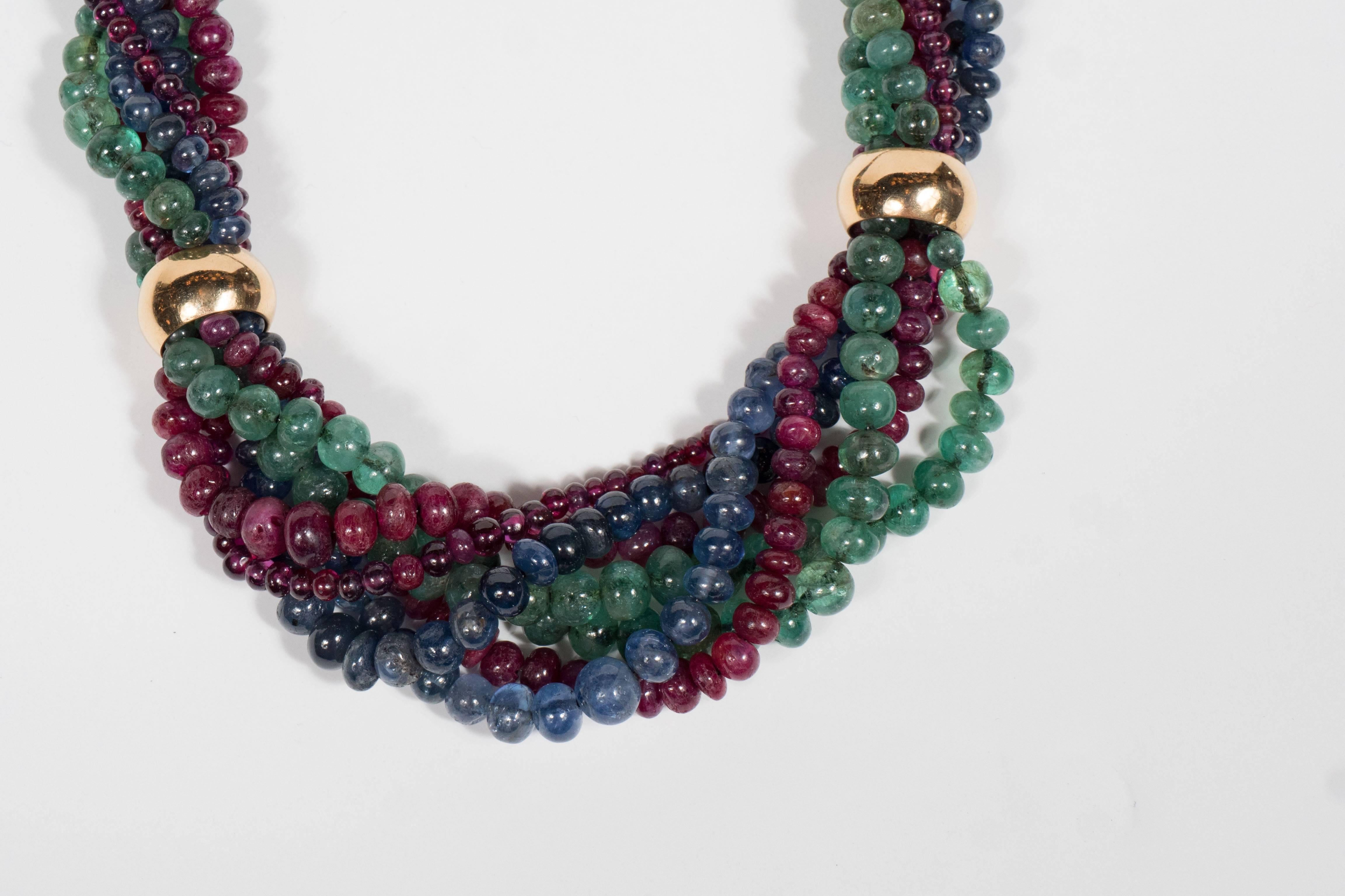 18 Karat yellow gold, emerald ,sapphire and ruby necklace comprising three strands of ruby beads and two strands of emerald beads, spaced by six gold rings, internal circumference approximately 20 inches with French assay and workshop marks. The