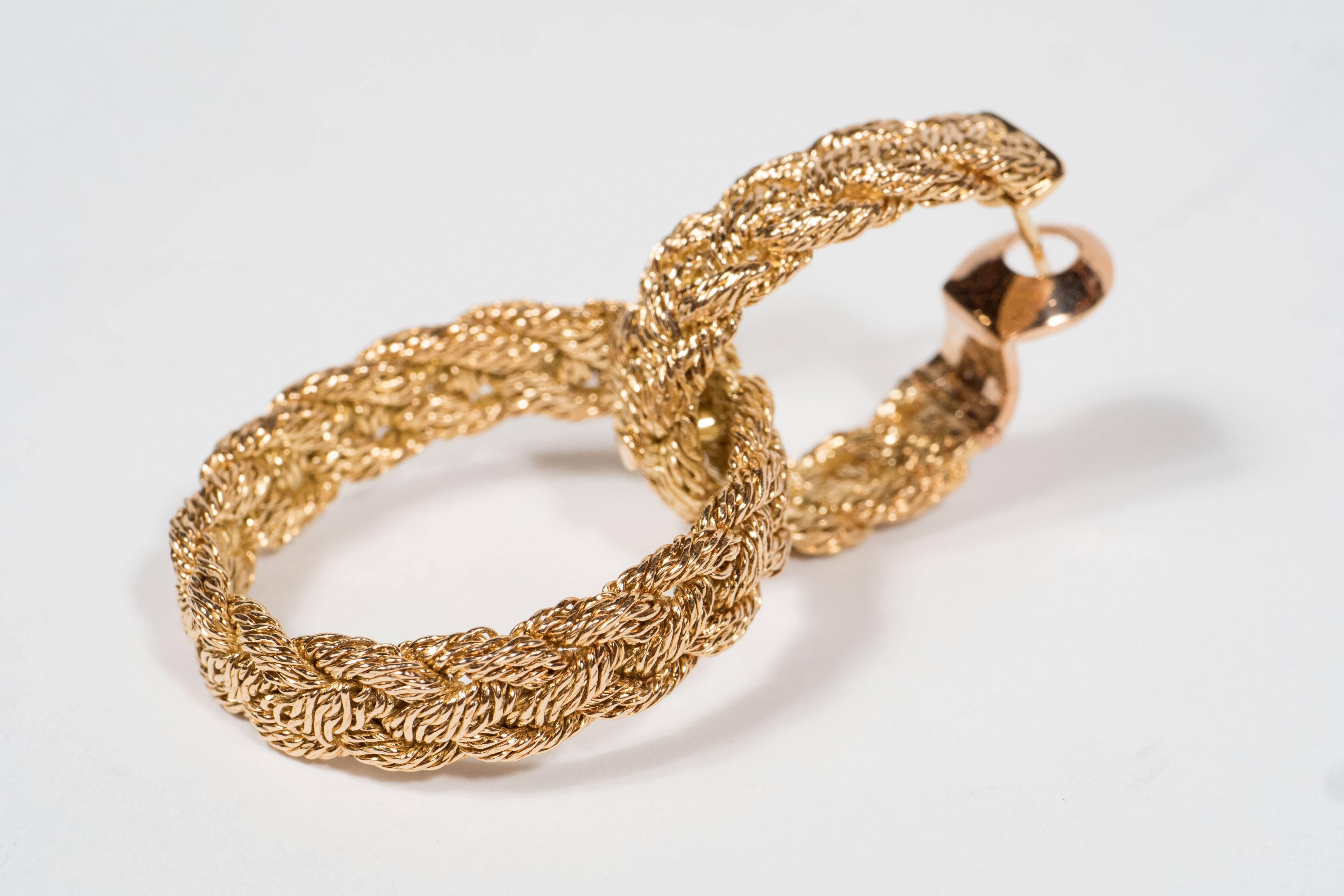 These stunning earrings feature a double loop design in woven 18k yellow gold. They are comprised of braided gold twists in an elegant door-knocker design. They are currently fitted for pierced ears but could be converted to clips. They are signed