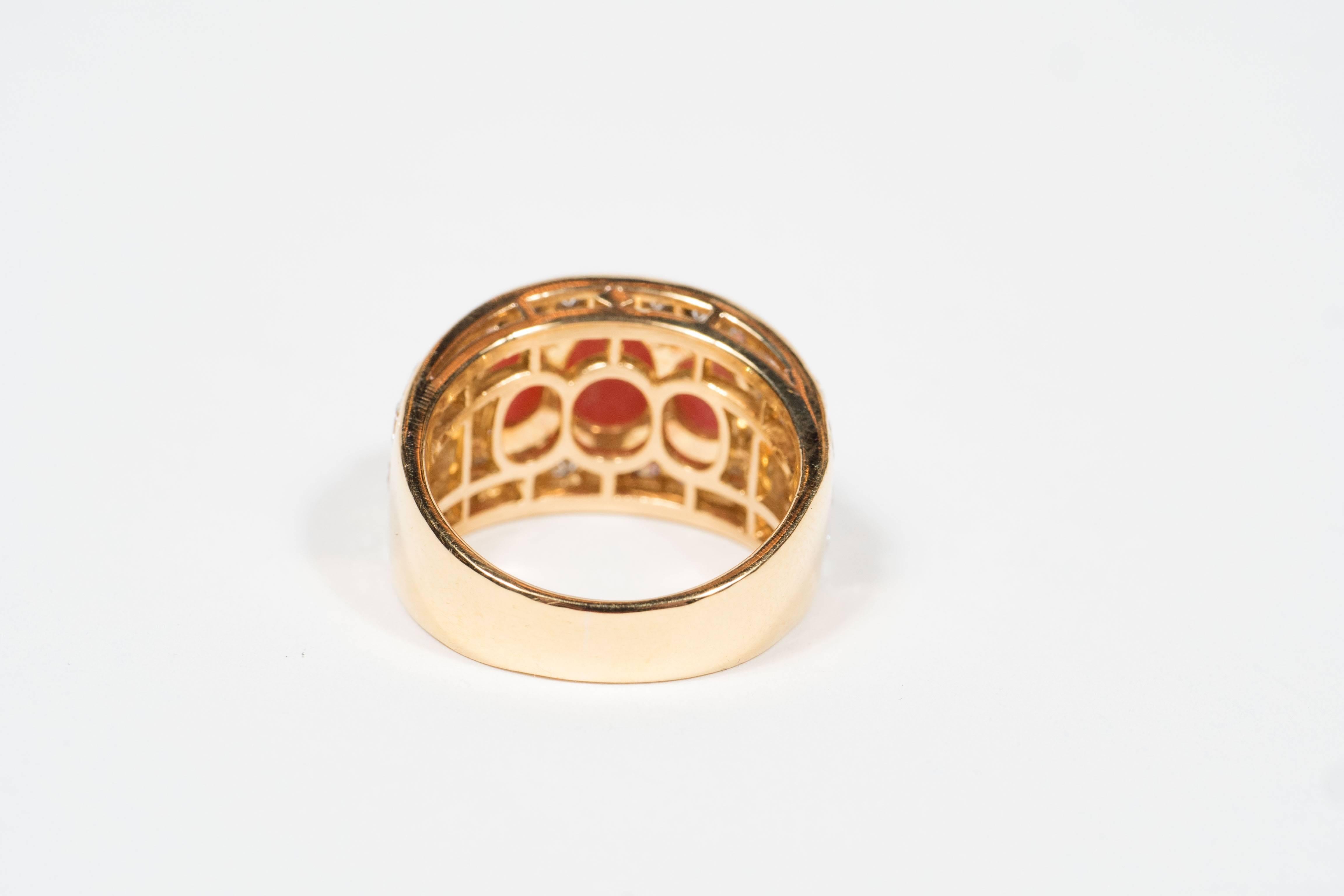 This stunning Mid-Century modernist Bulgari ring is made in Italy of 18k yellow gold centering 3 oval coral cabochons measuring approximately 7.9 by 5.6 to 7.0 by 4.4 mm, accented by 32 round and 4 baguette diamonds weighing approximately 1.55