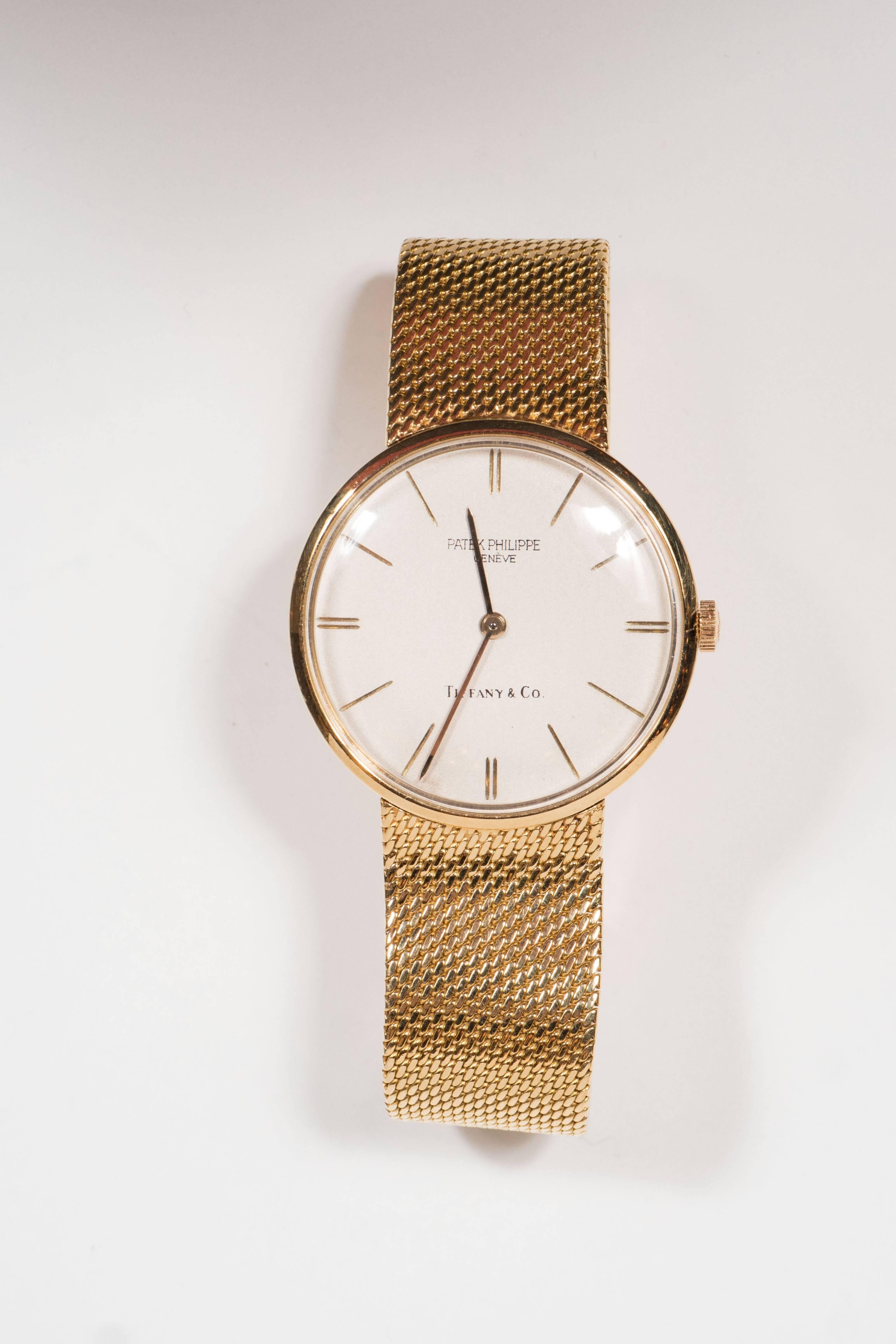 This Mid-Century modernist wristwatch is manual movement by Patek Phillipe, with a case diameter  of 32mm, dial and clasp signed Patek Phillipe and dial additionally signed Tiffany & Co. It can be worn unisex. The bracelet is a gold mesh and it fits