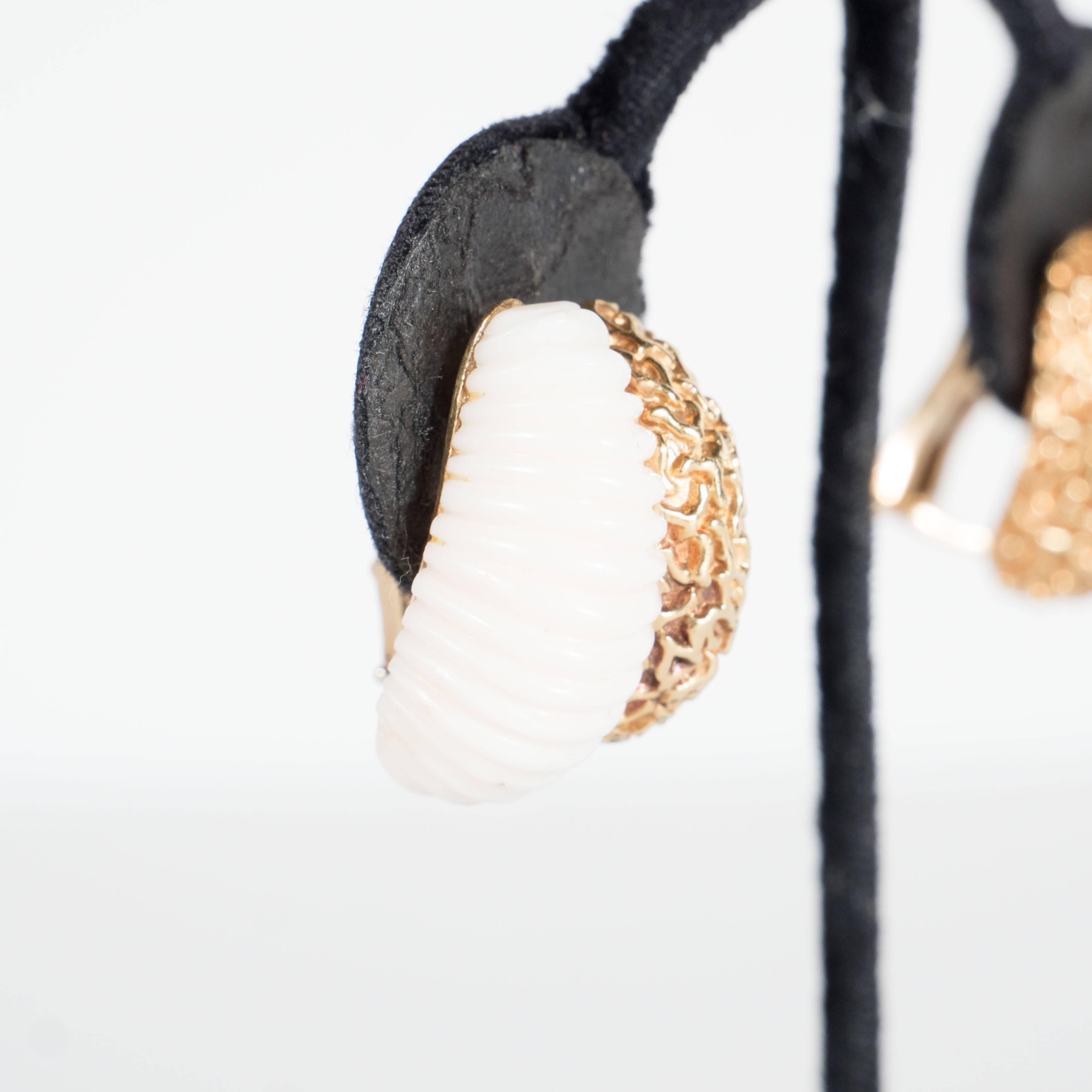 These very sophisticated pair of earrings feature a carved scrolled half hoop of white coral paired next to a textured half hoop design of 18k yellow gold with a design mimicking natural coral.They are in excellent condition.