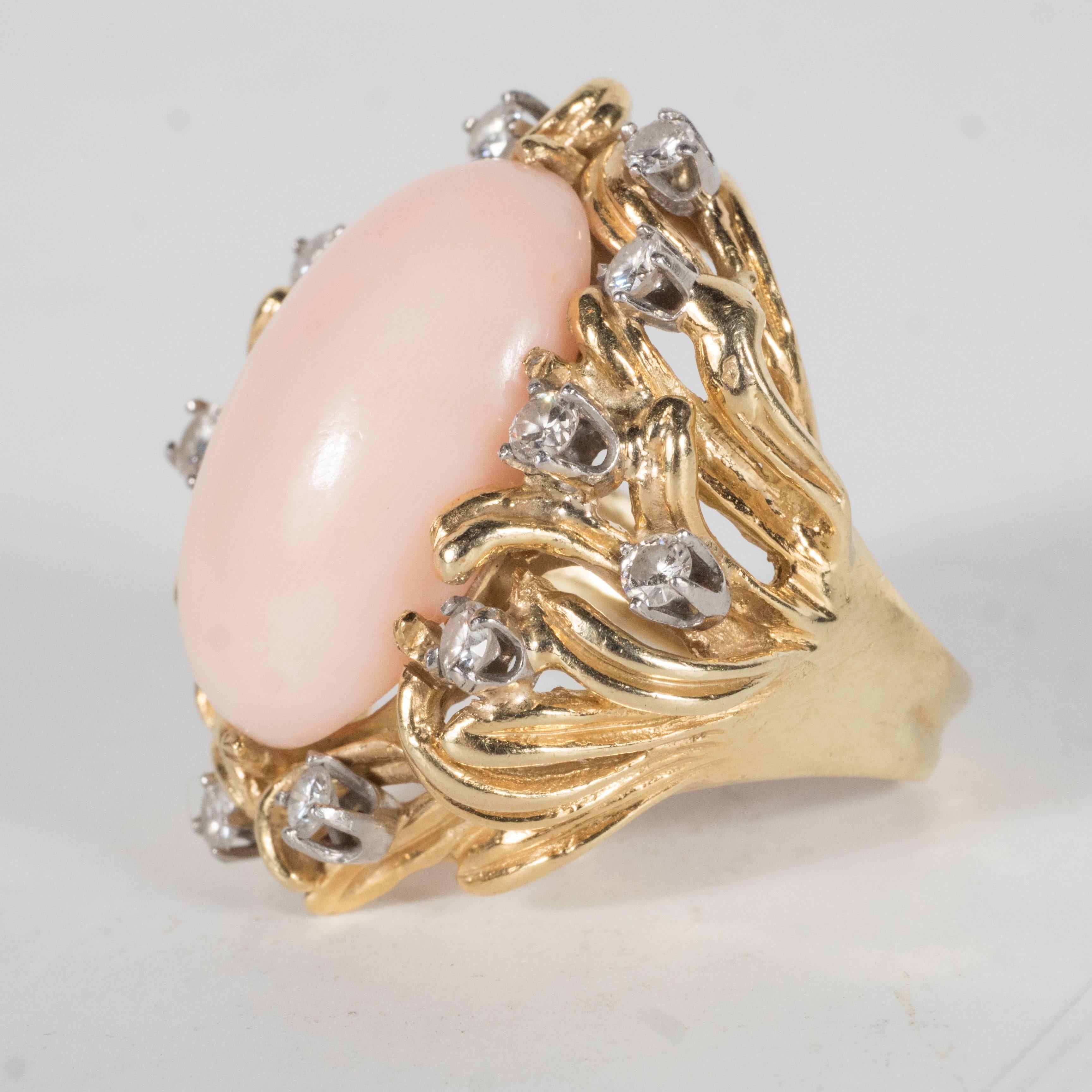 This Mid-century cocktail ring features an domed angel coral stone set in a 14k yellow gold designed with stylized foliate tendril details supporting 12 full cut fine diamonds. This ring is approximately a size 6 but the purchaser can size to