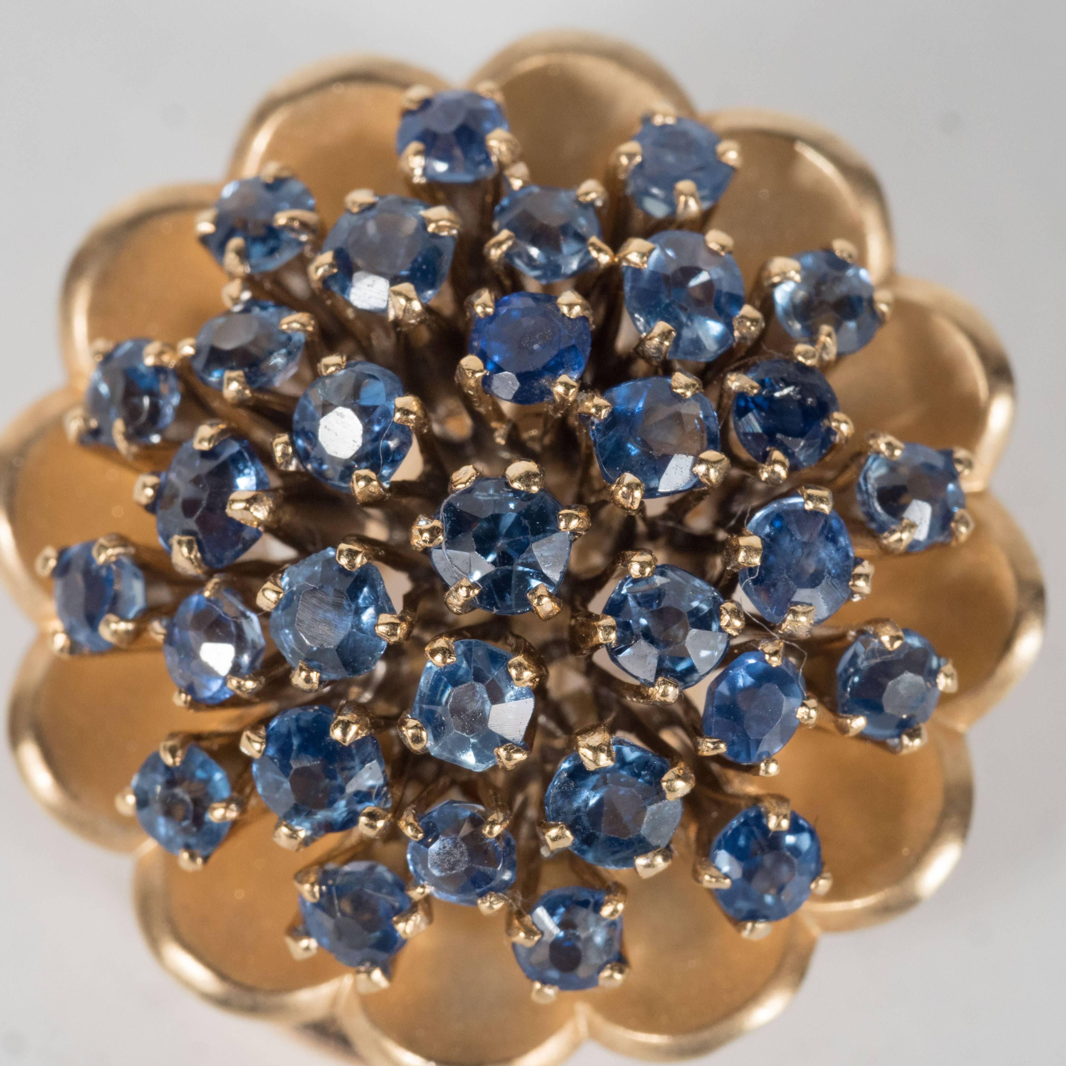 These Mid-Century modernist pair of 18k yellow gold and sapphire ear clips are made in Austria and were purchased in 1968.They are designed as a cluster of numerous round sapphires set in a 18k yellow gold stylized floral back.These  ear clips have