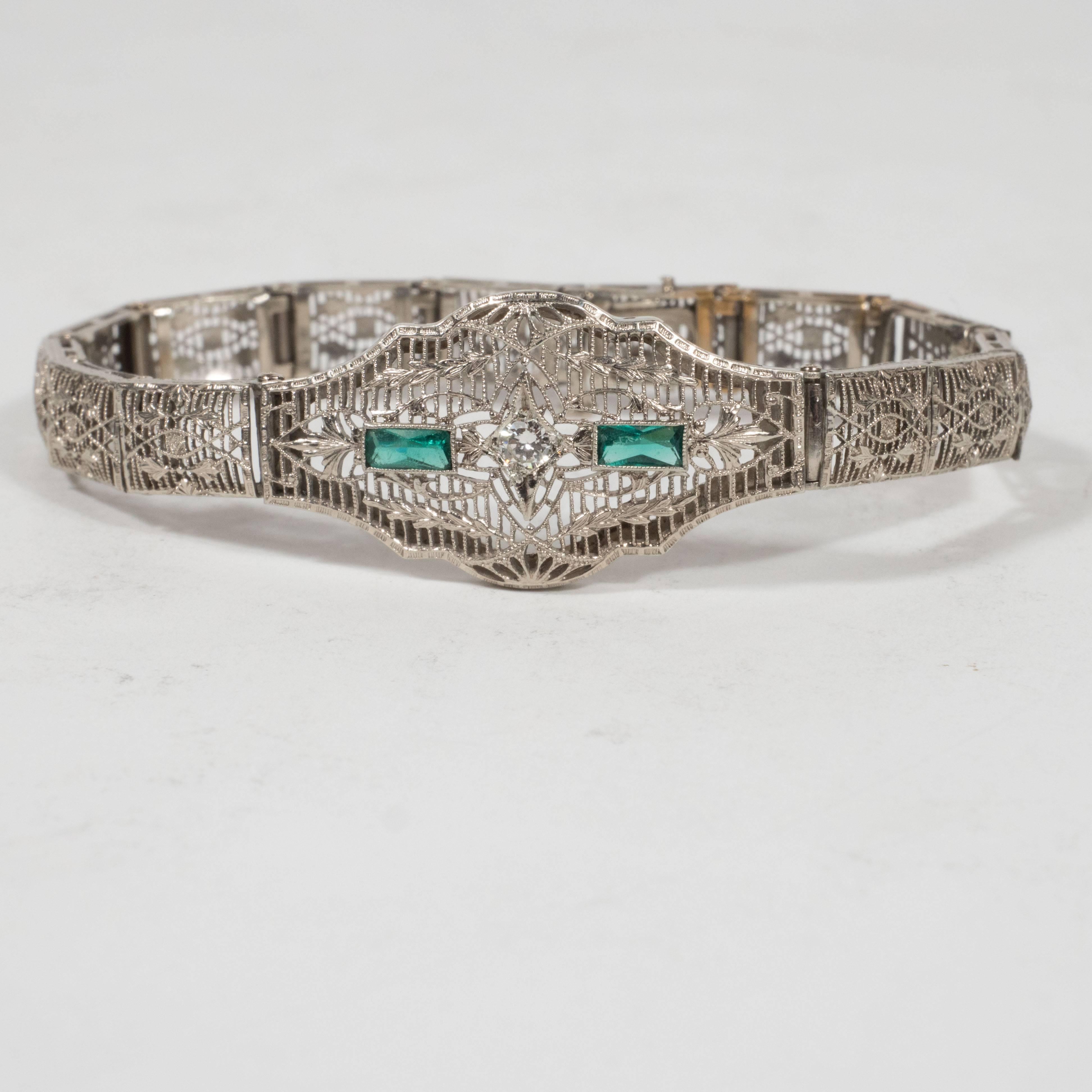 This gorgeous Art Deco bracelet features a central ten point brilliant white diamond placed in a star shaped setting which is flanked by two step cut synthetic emeralds on either side, weighing a total of 30 points. A the top and bottom of the