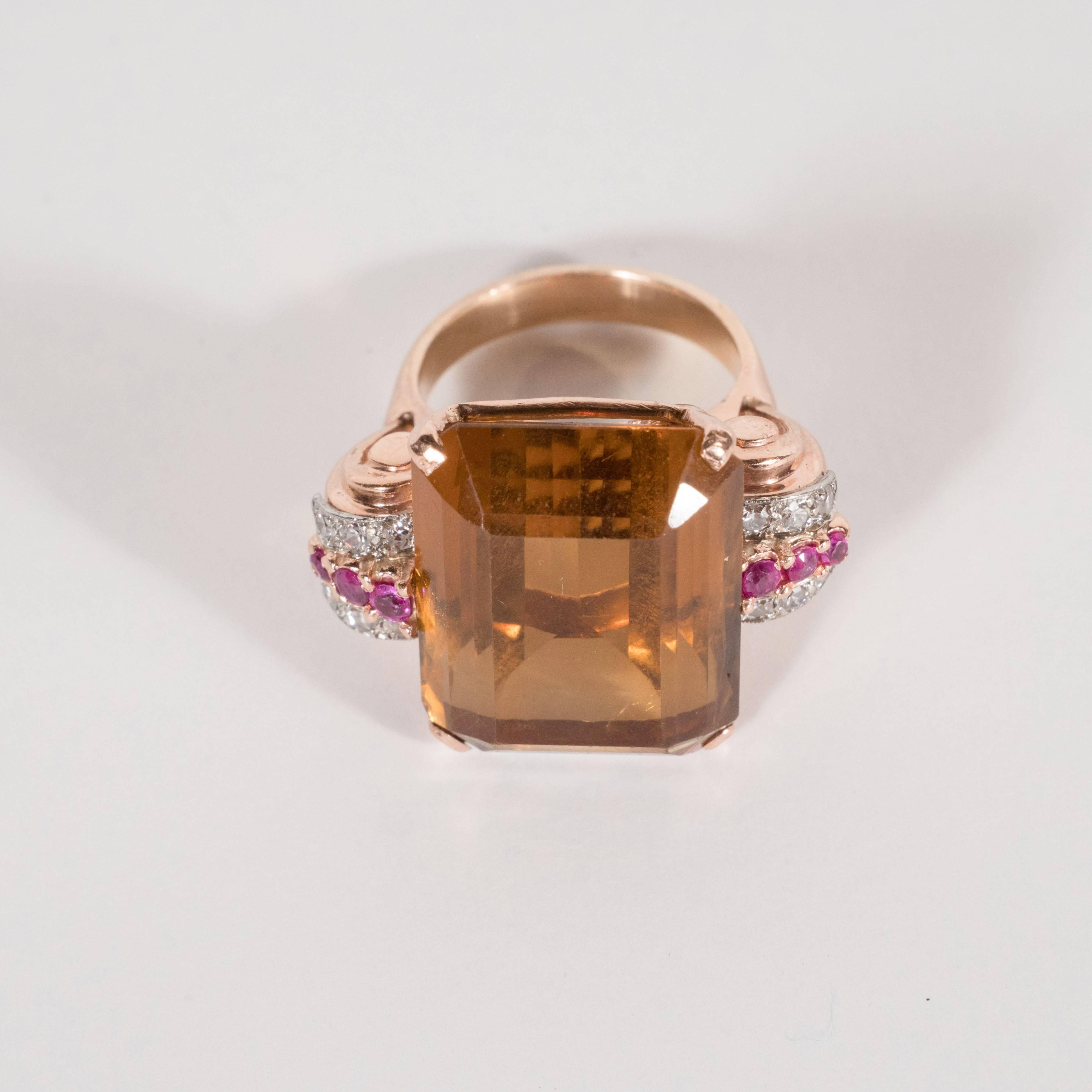 This magnificent ring features a large emerald cut topaz (approximately 25 carats) in a rich amber hue flanked by two scroll form shoulders holding 20 points of single cut diamonds as well as 20 points of brilliant cut rubies.  The diamonds exhibit