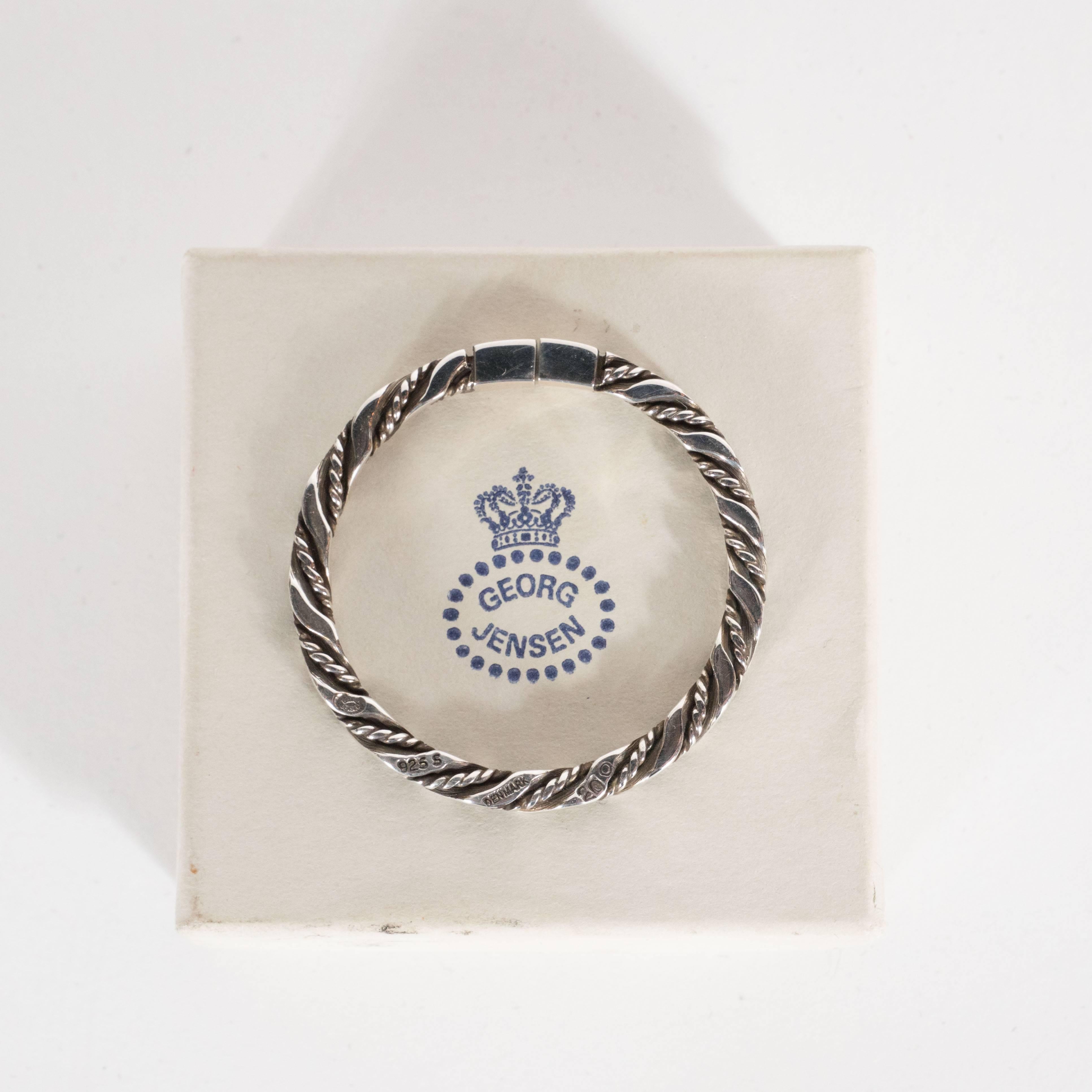 This elegant key ring was realized circa 1960 by the esteemed Danish silversmith Georg Jensen. Consisting of a simple circular form with a repeating braided pattern, this piece embodies the quiet sophistication that collectors of Jensen prize. The