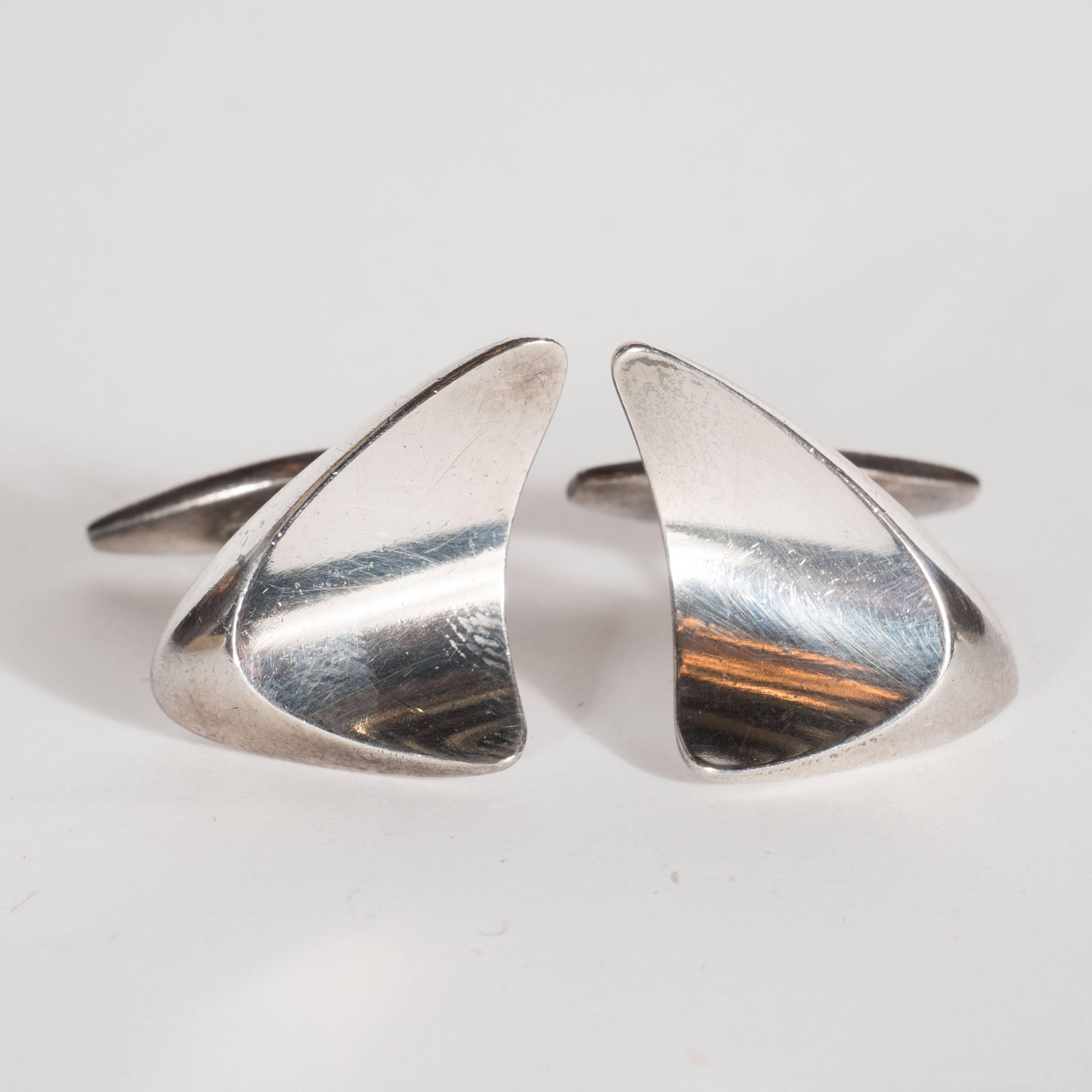 This sophisticated pair of cufflinks were realized by the esteemed Danish silversmith Georg Jensen, circa 1960.  Composed of a bowed and convex organic form, these cufflinks embody space age Mid Century Modernism- Eero Saarinen et al- at its finest.
