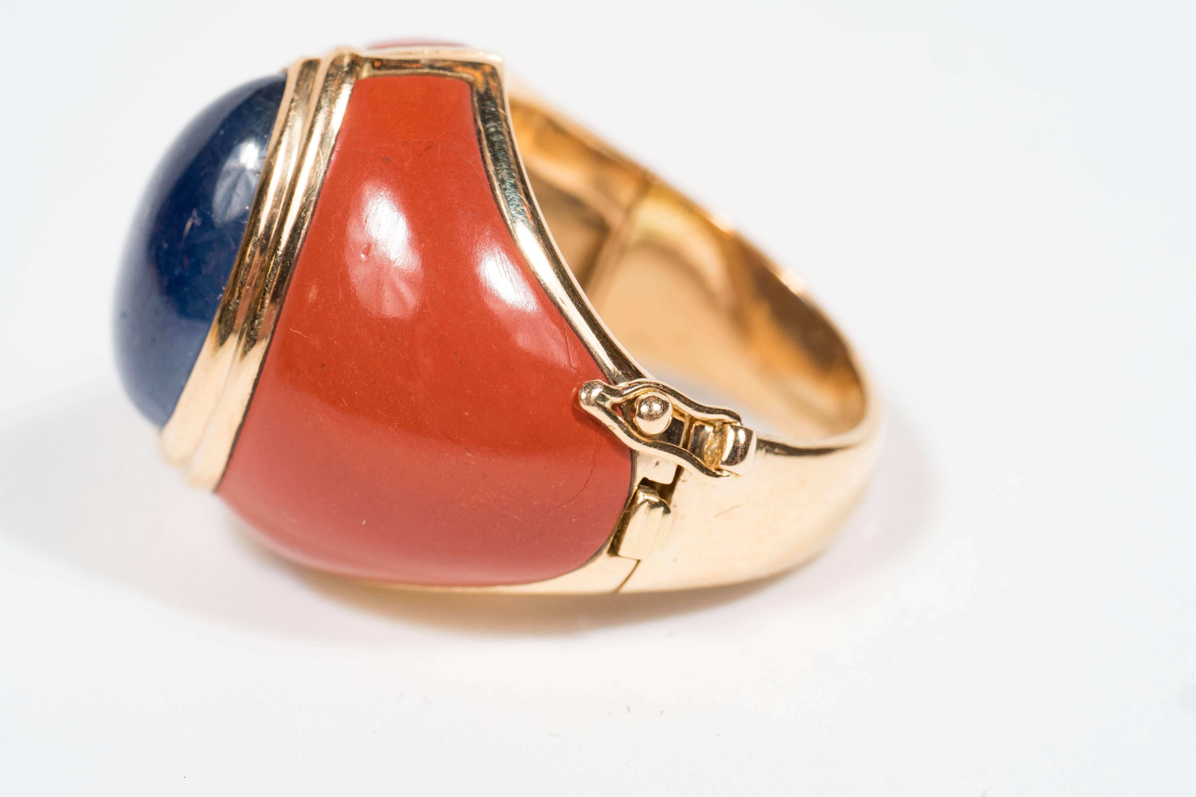 Hand crafted in France circa 1968, this sophisticated ring features a fine pear-shaped cabochon sapphire weighing approximately 12 carats, surrounded by 2 carved jasper plaques, all set in 18kt yellow gold.  The ring is hinged with a clasp to open