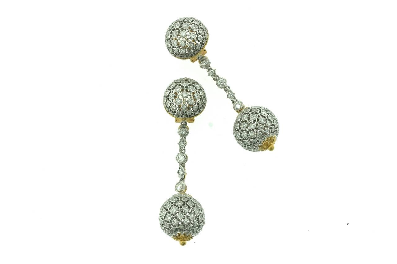 Buccellati 18k white gold earrings designed as diamond set half spherical tops of an open work style bordered by an etched yellow gold frame suspending five diamond links connected to a full spherical diamond set bottom with yellow gold finials of a