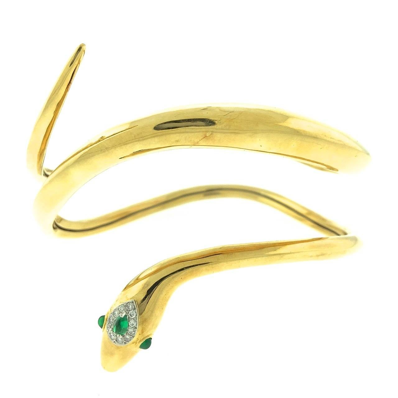 Designed by Donald Claflin for Tiffany & Co., this 18k gold coiled upper arm bangle is a rare piece from 1972. Set with emerald eyes and a headpiece of cabochon emeralds ringed with diamonds this stylish bangle is in perfect condition and comes in