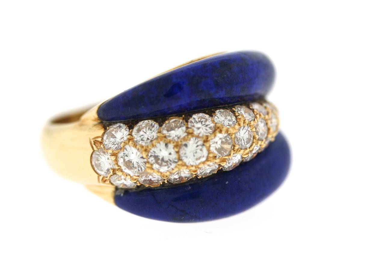 Van Cleef & Arpels, Paris 18k gold ring of a bombe shape with two curved and rounded sections of lapis lazuli centering a diamond pave set section with 29 round white brilliant round diamonds totaling approximately one carat. ⅝