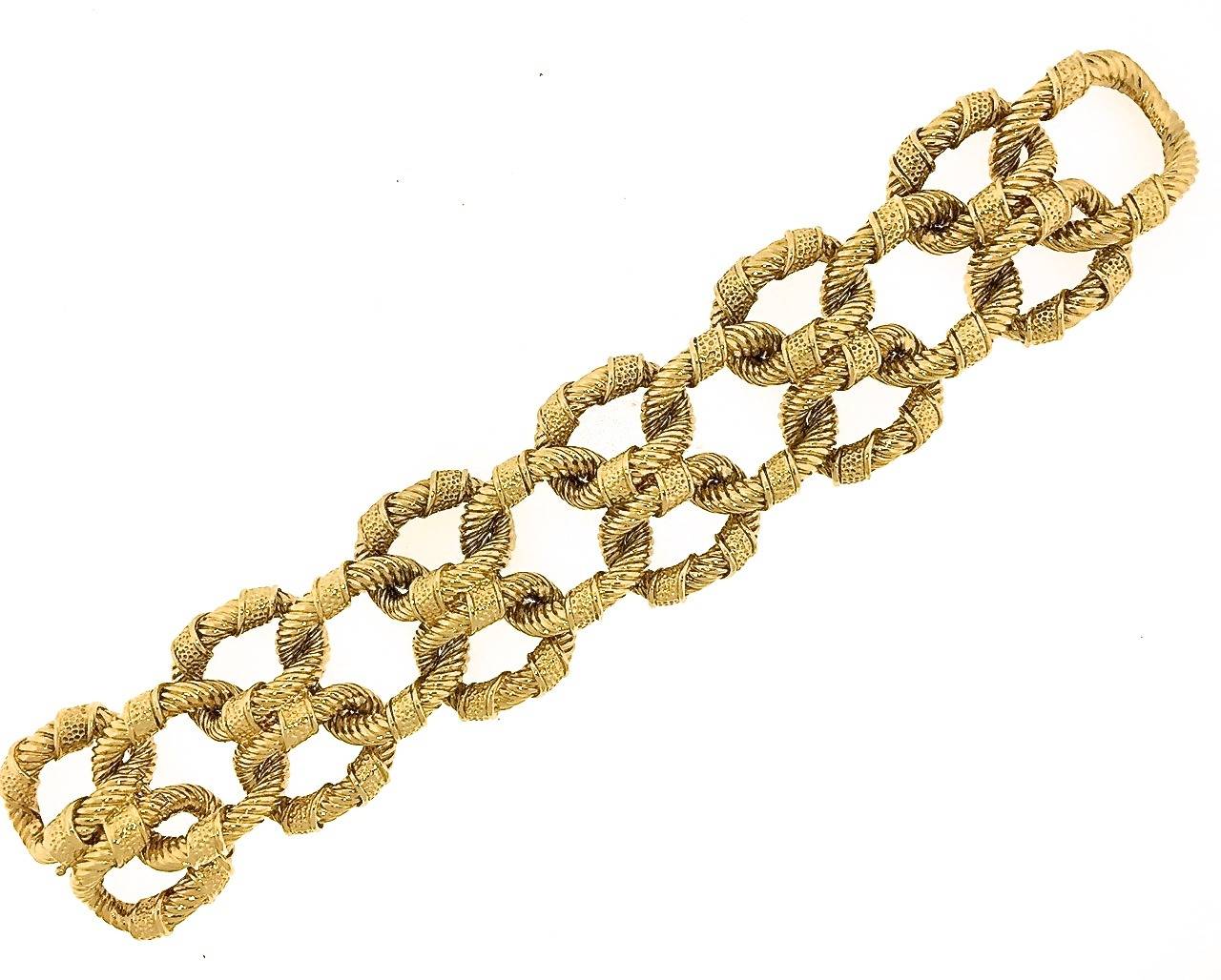 Van Cleef & Arpels 18k gold bracelet designed as a double row of joined, oval, textured gold links alternating with larger, oval, textured gold links. Each link is embellished with two textures; a ribbed striated finish wrapped in ribbons of gold