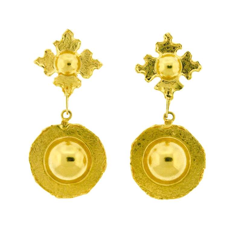 Interchangeable 22k gold earrings with two bases: one in a pattern just larger than the base, and the other a hollow, circular sphere radiating a flat, round border. 
Jean Mahie is renowned as an artist jeweler, a term colloquially used to blend
