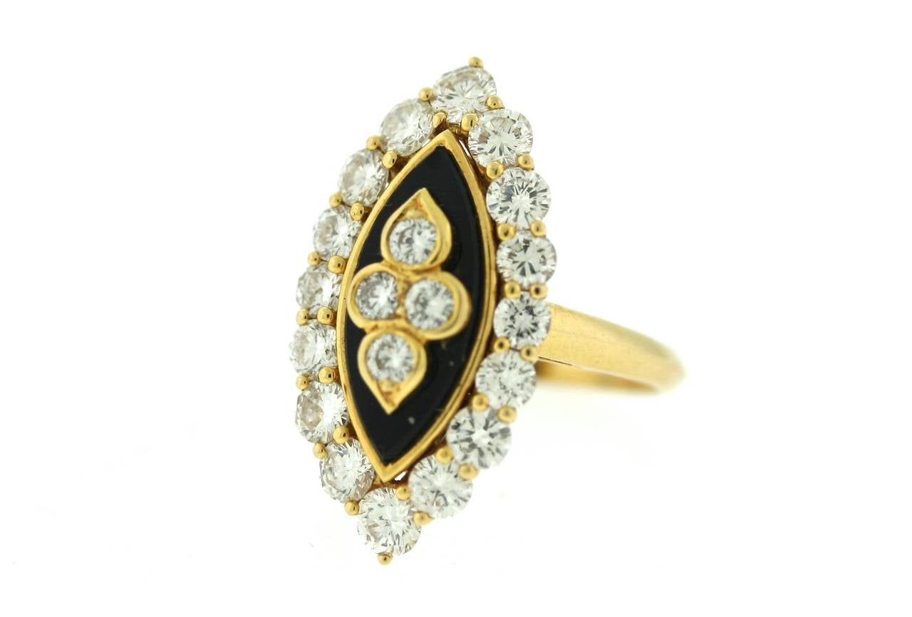 Van Cleef & Arpels Paris 18k gold ring with a center navette black onyx surrounded by 16 round brilliant cut diamonds and centering four additional diamonds in a stylized clover shape. Signed VCA FRANCE and numbered with French hallmarks and maker's