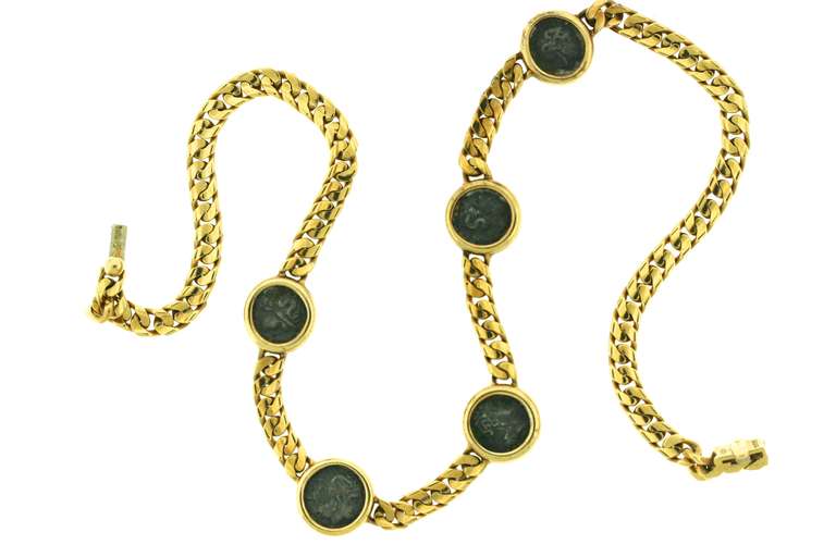 A classic design by Bulgari from the MONETE COLLECTION of the 1970s. Set in 18k gold this curb link chain is set with five ancient Roman coins. The bezels of each coin are engraved with the name of the figure on the coin. This iconic collection is