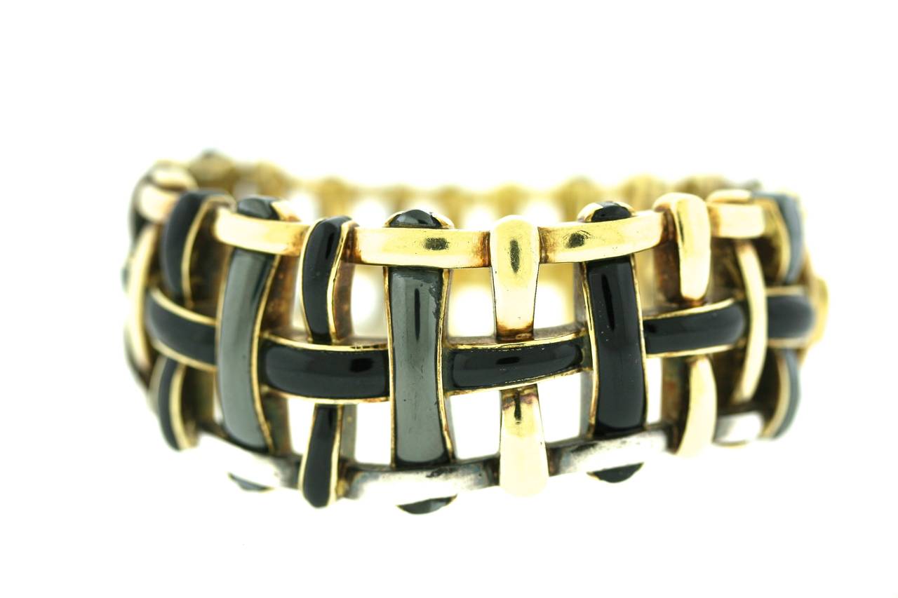 Angela Cummings for Tiffany & Co 18k gold hinged bangle bracelet of a stylized basketweave design with inlaid hematite and sterling silver and inset black onyx. 
Cummings used this type of loosely woven design, overlaying pieces of gold or other
