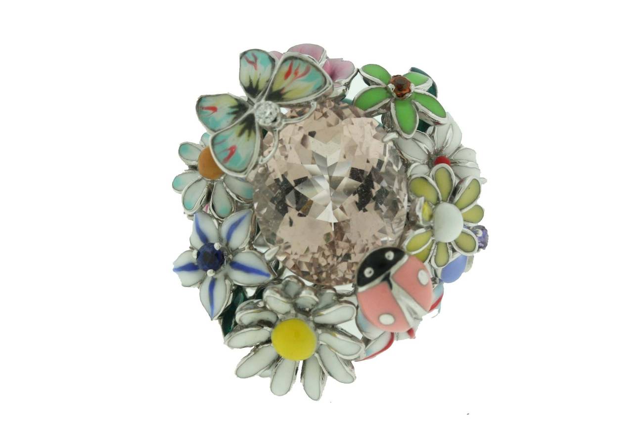 Dior 18k white gold ring designed as a garden of enamel flowers, butterfly and lady bug centering a faceted pink morganite stone. The flowers and butterfly also have gem set centers of a diamond and four multi colored sapphires. This is an iconic