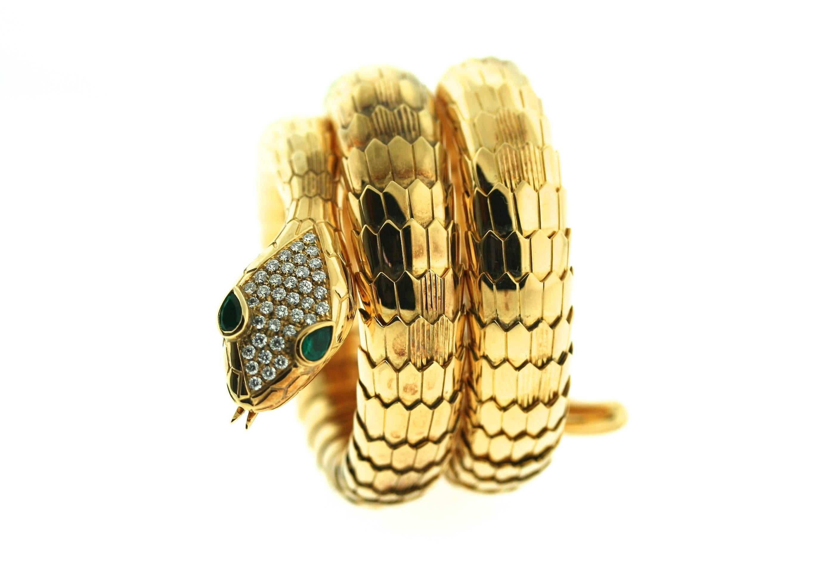 Illario 18k gold coiled serpent bracelet with both polished and textured scales. The serpent's head is pave set with diamonds and faceted emerald eyes. The tension mechanism of the bracelet allows for flexibility in both movement and fit. Illario is