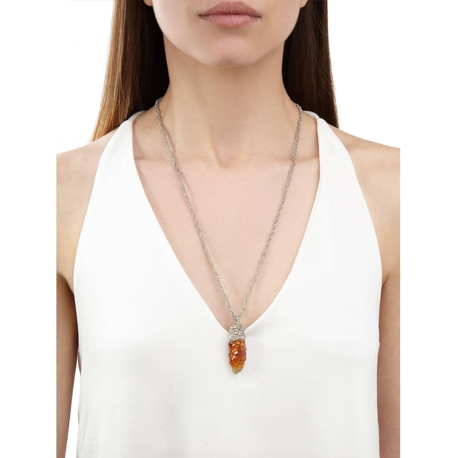 A beautiful one of a kind necklace featuring a cluster of vivid orange spessartine garnets which have grown over a quartz crystal, set in molten-like granules of silver. The pendant hangs from a plaited silver faceted ball chain.

Crystal