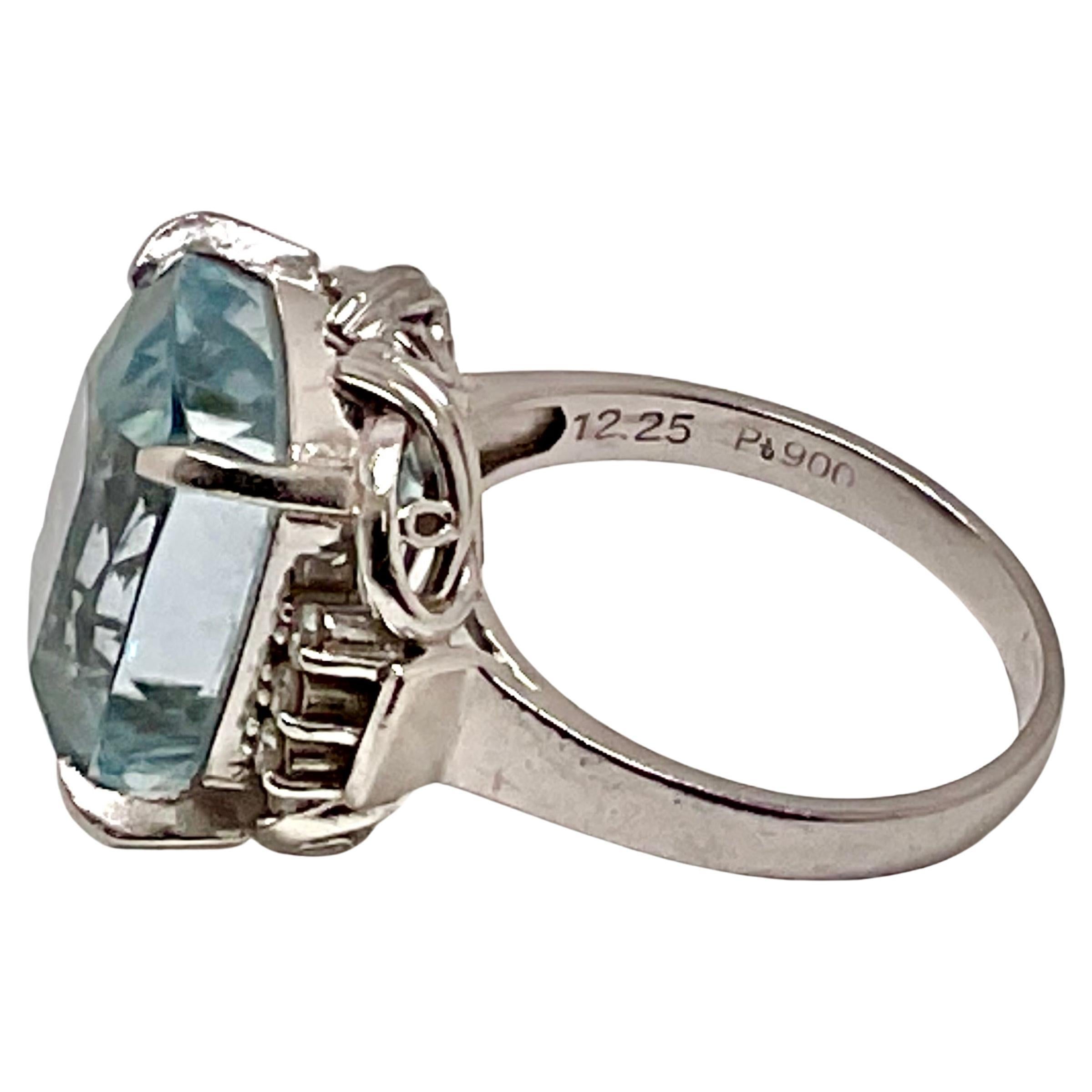 Este llamativo anillo de cóctel vintage tiene en el centro una aguamarina talla esmeralda, de aproximadamente 7 quilates, en un engaste de cuatro garras. Los hombros están decorados con un lazo y engastados con nueve (6) diamantes redondos de talla