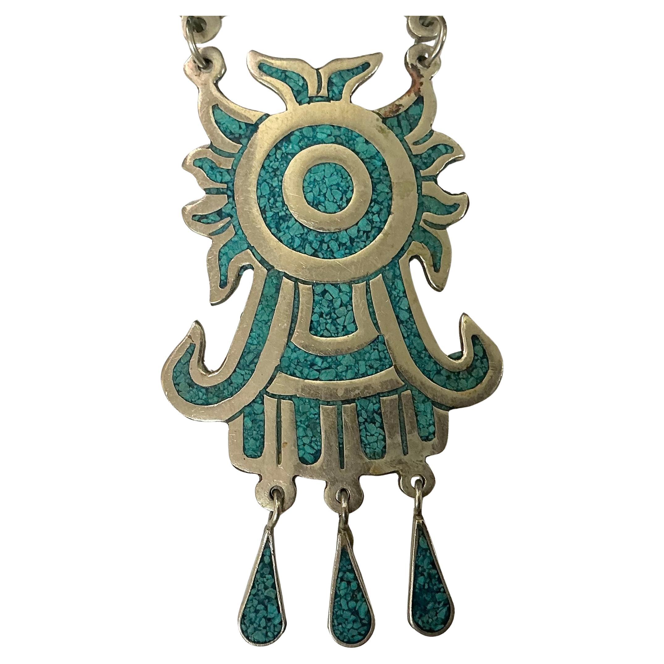 Collana con intarsio di alpaca messicana in argento sterling e turchese. La collana è realizzata in argento Alpaca e presenta un intricato turchese dalle tonalità vivaci. La collana è progettata con segmenti ampi e curvi che conducono a un audace