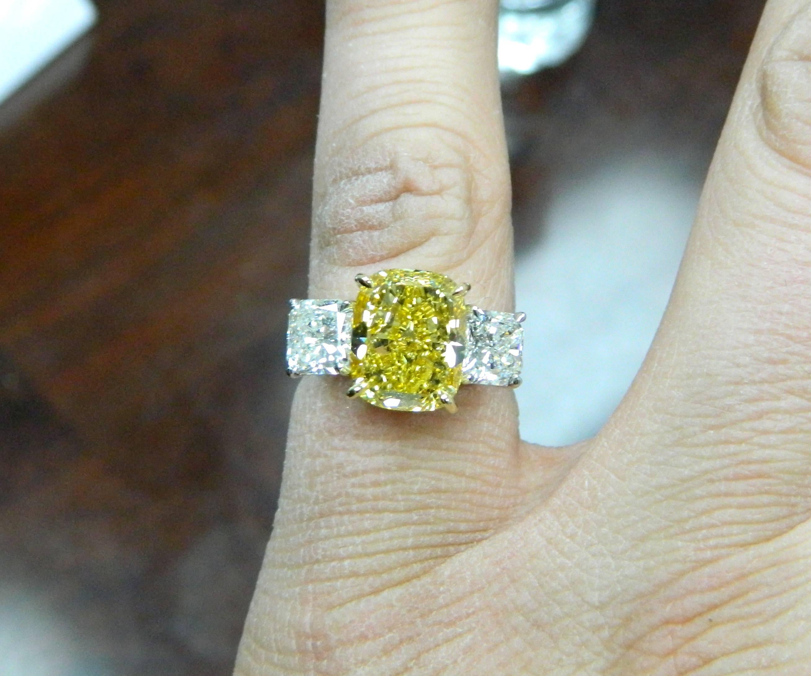 A bold and rare GIA Certified, 5.02ct Fancy Deep Yellow VS2 cushion cut diamond, flanked by two GIA certified radiant cut diamonds weighting 1.01ct and 1.00ct.  Mounted in platinum and 18kt yellow gold.