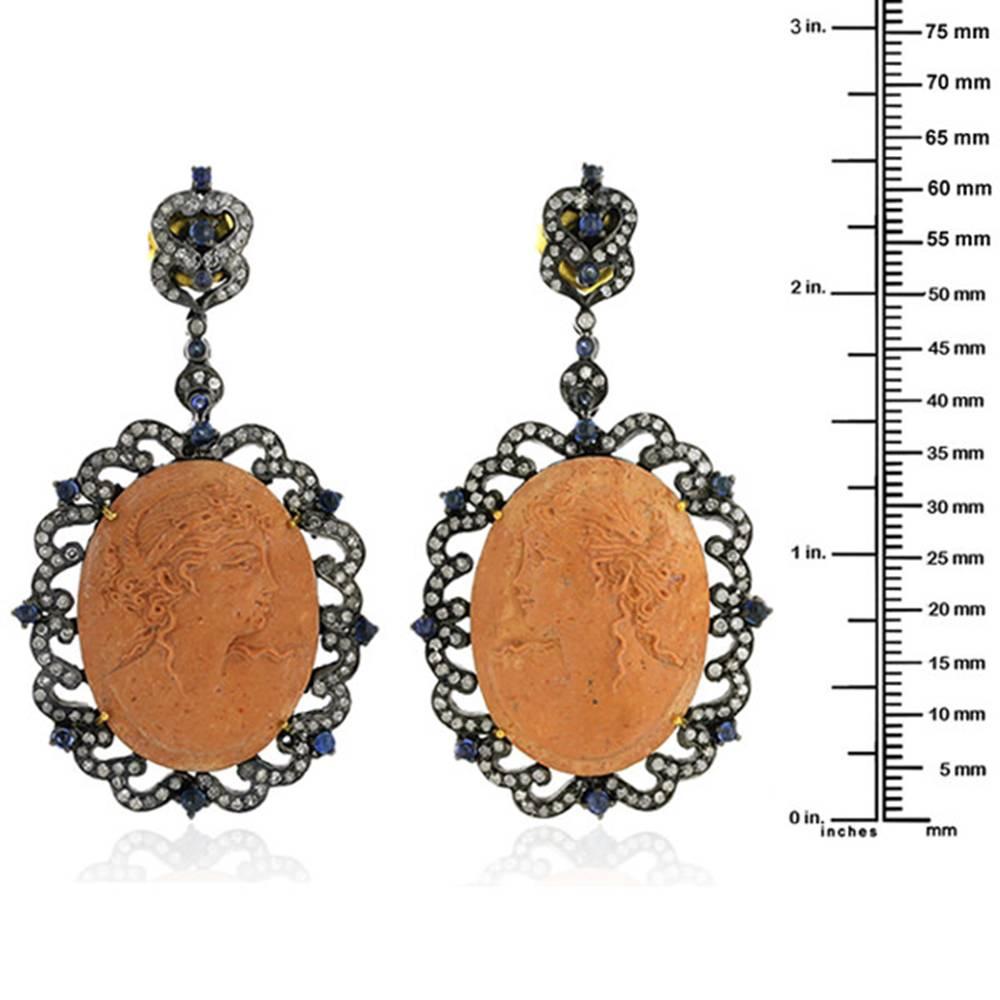 Hand carved beautiful lady face carved Lava Cameo Diamond Earrings with Blue Sapphire. This earring has push and post. 
18k:1.68g
D:2.35ct
Slv:15.51gm
Sapphire : 1.40cts
Cameo:55.15cts
