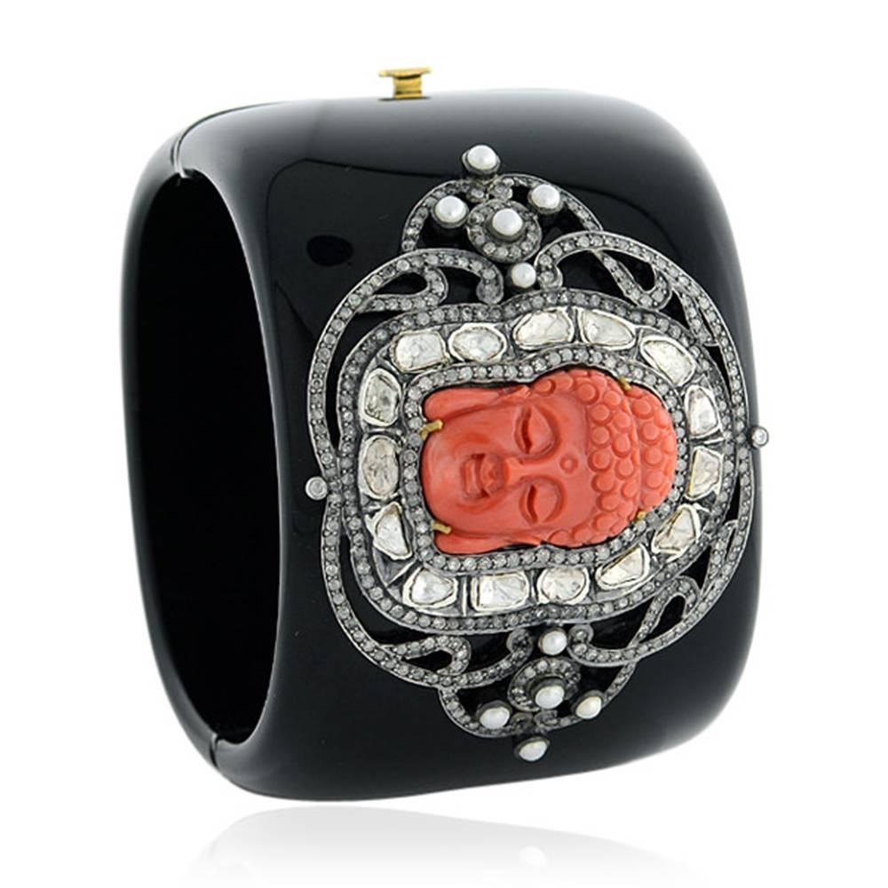 Beautiful Broad Bakelite Coral Buddha Bangle with artistic frame of pave and rosecut diamonds and pearls around. This bangle is openable and fits very well on wrist as it is square in shape inside.

18k:2.85g
D:5.77ct
Slv:27.61gms
Bakelite -