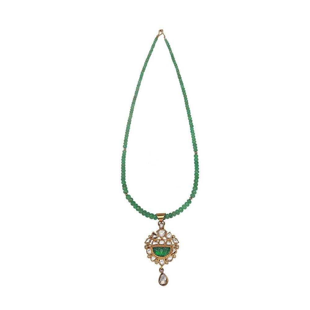 Sweet and pretty triangular shape carved emerald with polki diamond motif around on a faceted beaded emerald necklace is a very charming piece. The pendant has a very fine enamel art work on the back so you can wear the pendant reversible