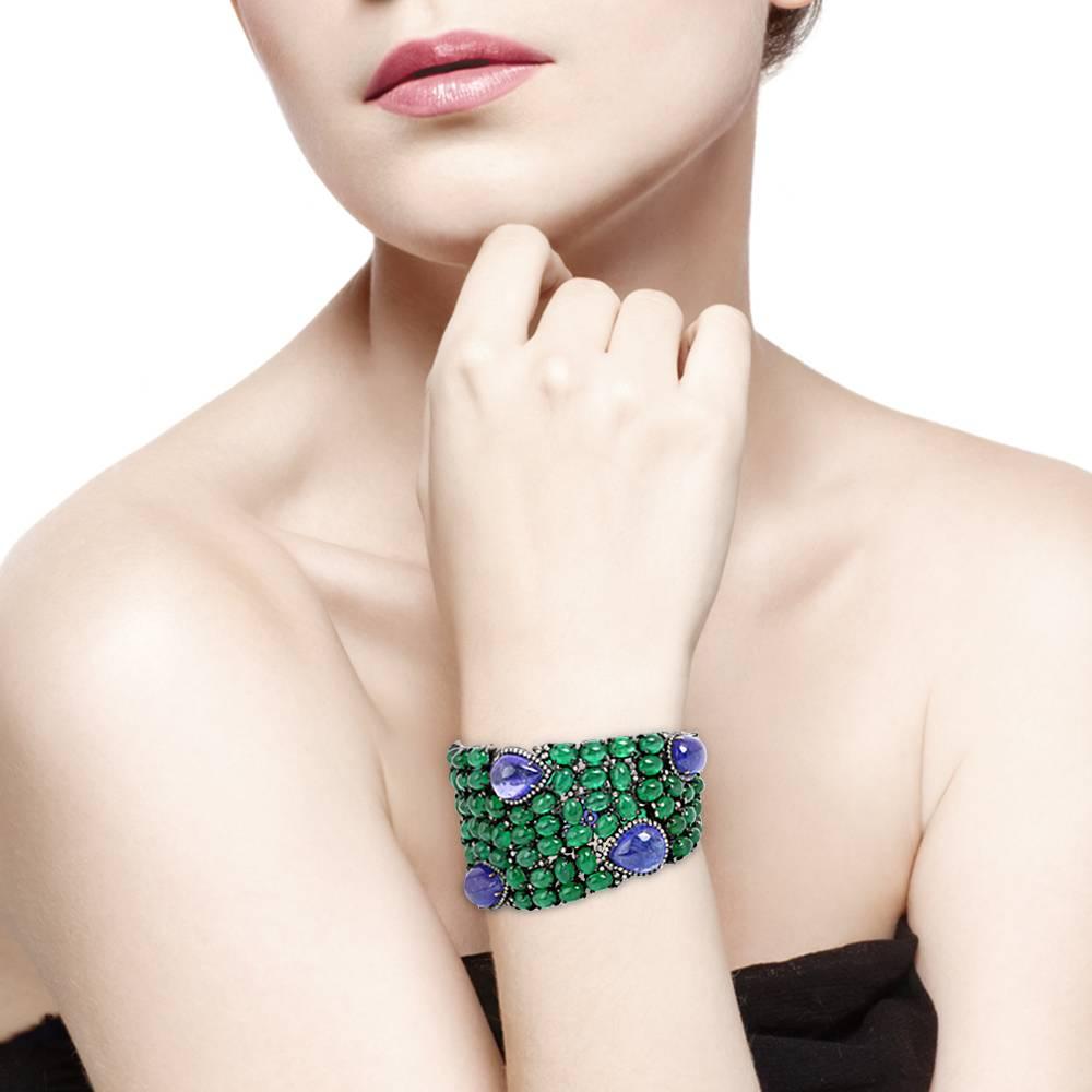 Our best seller Emerald and Tanzanite with diamonds tennis bracelet which narrows down on the wrist on both sides set in gold and silver. This stunning piece has cabochon emeralds and blue sapphire prong set with diamonds and is linked very safely