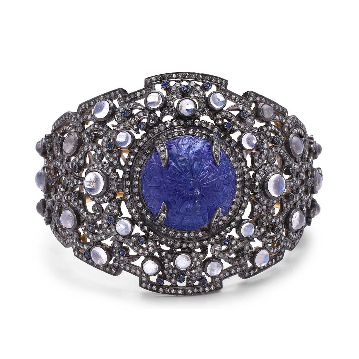 Super Luxurious Carved Sapphire Bangle studded with Diamonds & Moonstone is indeed a bold and beautiful piece. This bangle is openable and has two safety clasps. 

14k:15.26gms
Silver:47.67g
Diamond:6.92ct
Sapphire-1.80cts
Moonstone-81.82cts

      