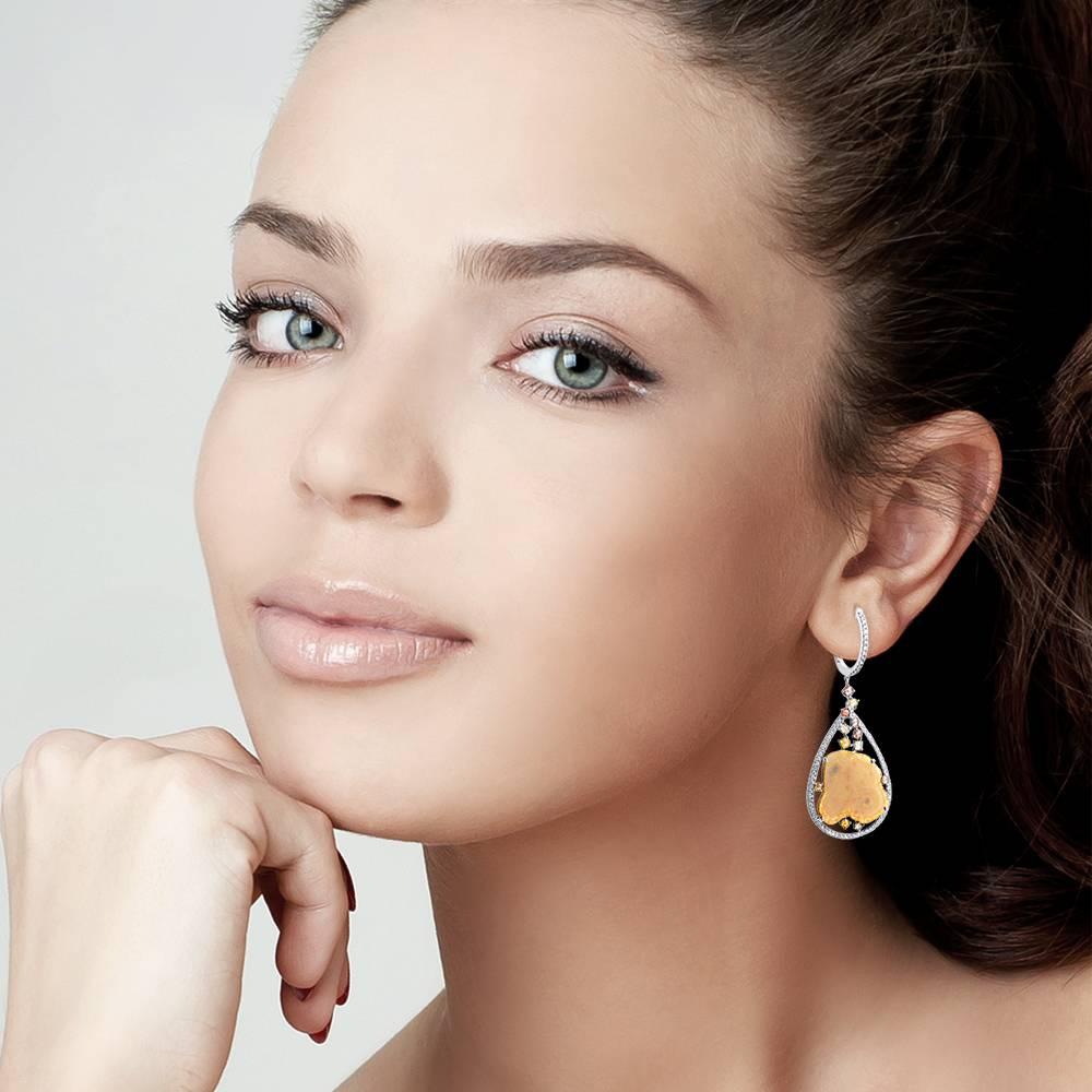 Delicate but a statement making yellow silce diamond earring with small full cut diamonds sprinkled around and framed in a pave pear shaped white gold frame. It has a hoop earring closure on top with a very safe pressed lock.