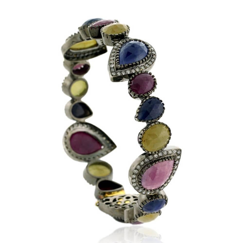 Multi color and multi shaped openable bangle with diamonds around. This bangle is made in silver with closure and safety clasps in 18K Gold. Pair it with any color dress this season and you will be good.

18k:1.74g
Diamond: 1.82ct
Sapphire: