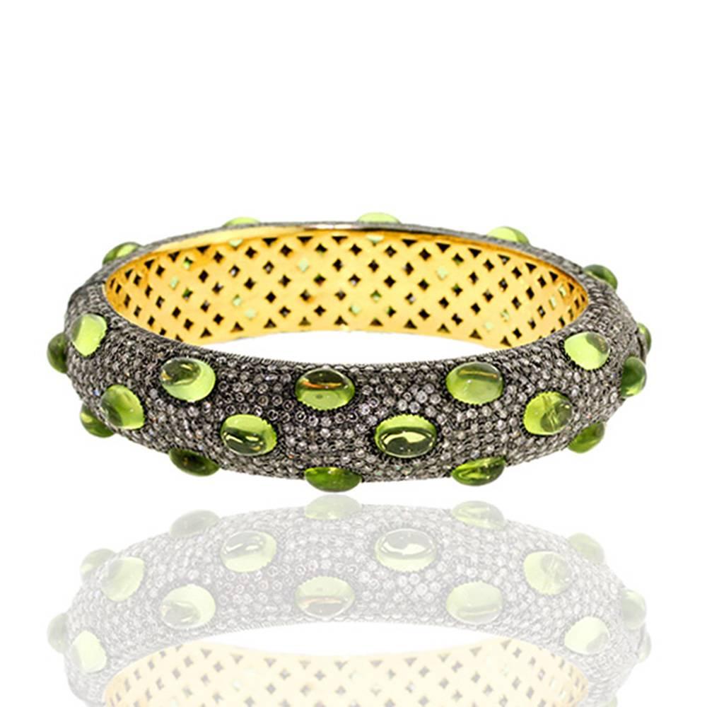 Chic and classy this cabochon peridot with pave diamonds bangle is oval in shape and opens on side and easy to wear on. This bangle has safety clasps on side.

 14k:8.1gms
Diamond: 10.27ct
Slv:22.38gm
Peridot:36.96ct