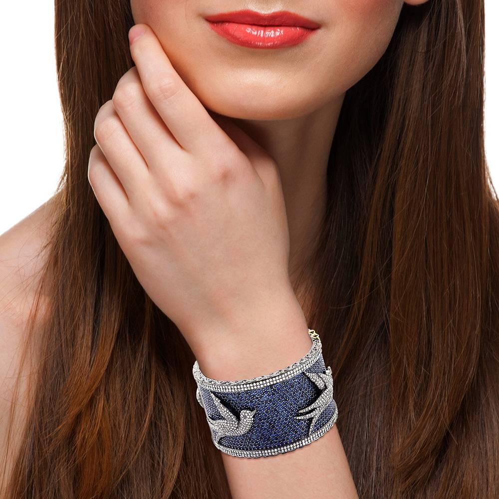 Diamond Bird motif Bangle with pave Blue Sapphire, this bangle is unique in a way depicting freedom and fun. This bangle has easy closure system with safety locks on both the sides.

18K: 3.45g
Diamond: 10.080ct
SiIver: 118.158g
BLUE SAPPHIRE: