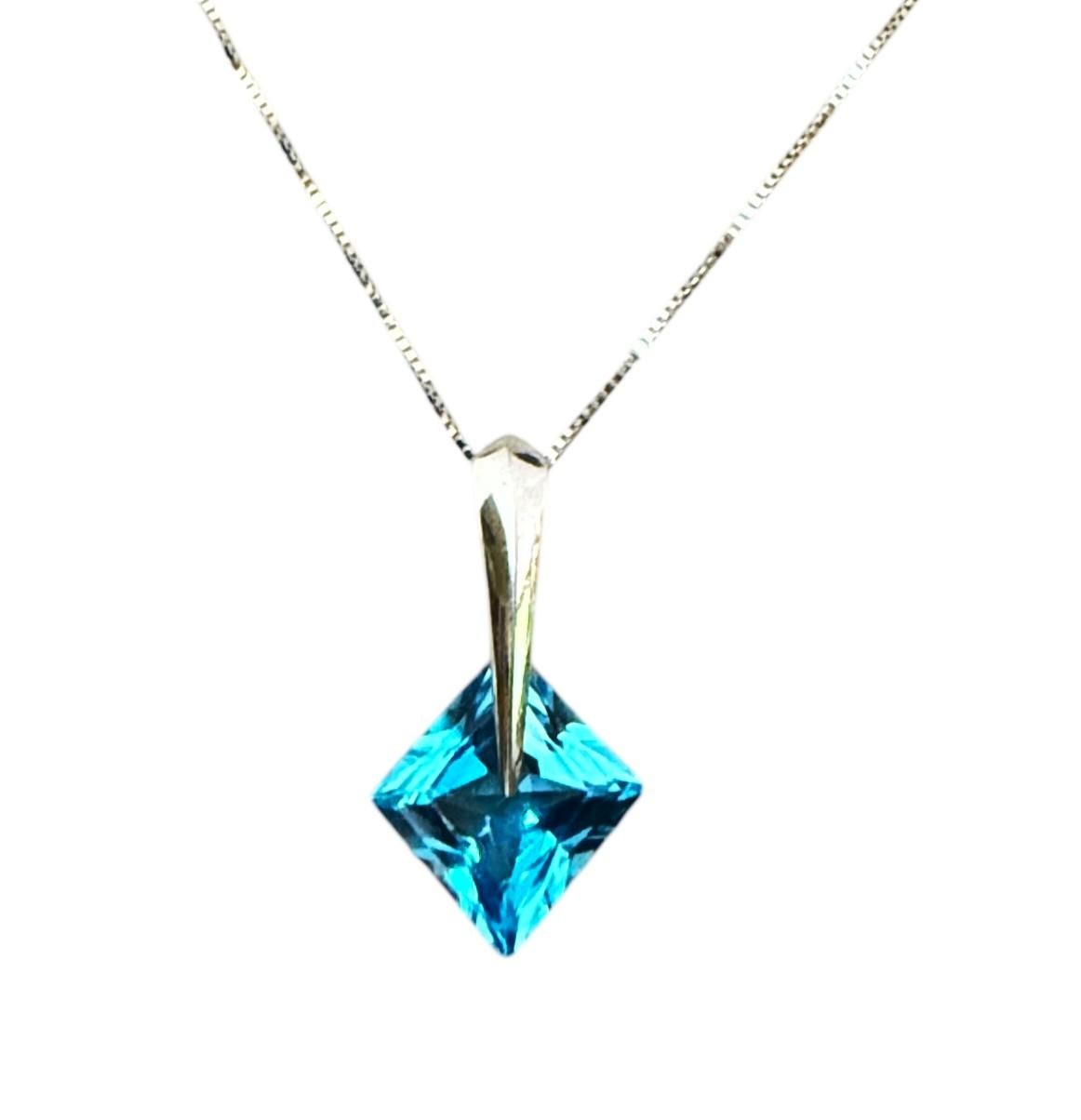 J'adore le design de ce collier.  Elle est réalisée en or blanc 14k et comporte une pierre centrale en topaze bleue de taille trillion placée en diagonale dans la monture.  La pierre mesure 8,5 x 8,5 mm et pèse 3,4 carats. Il est magnifiquement
