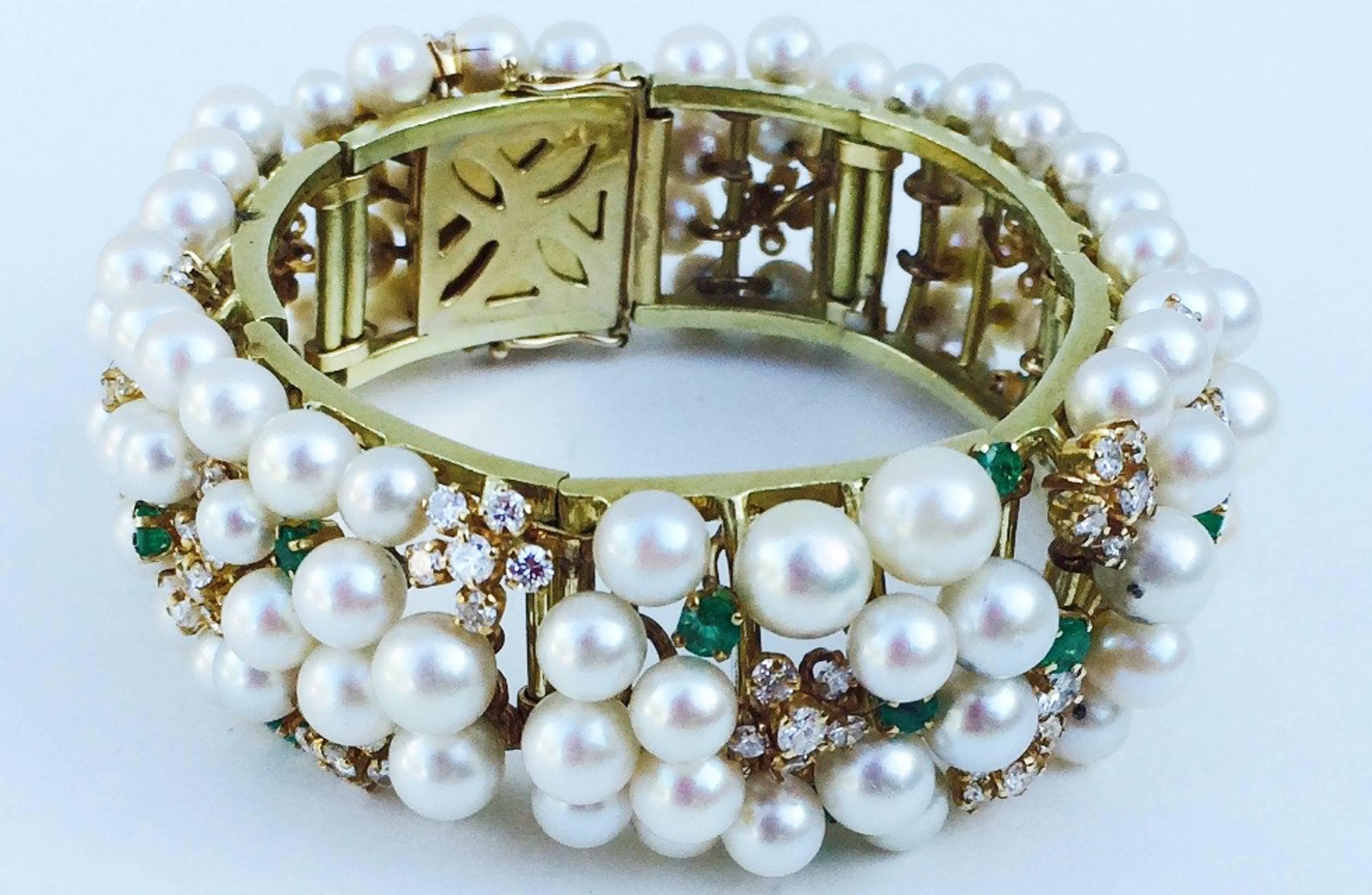 A exquisite mid-century pearl encrusted cuff bracelet. Hinged yellow gold item completely covered with pearls (3mm to 6mm), sparkling diamonds (approx. 5.71ctw) and emeralds (approx. 1.5ctw). Original hidden push button clasp and side locks intact.