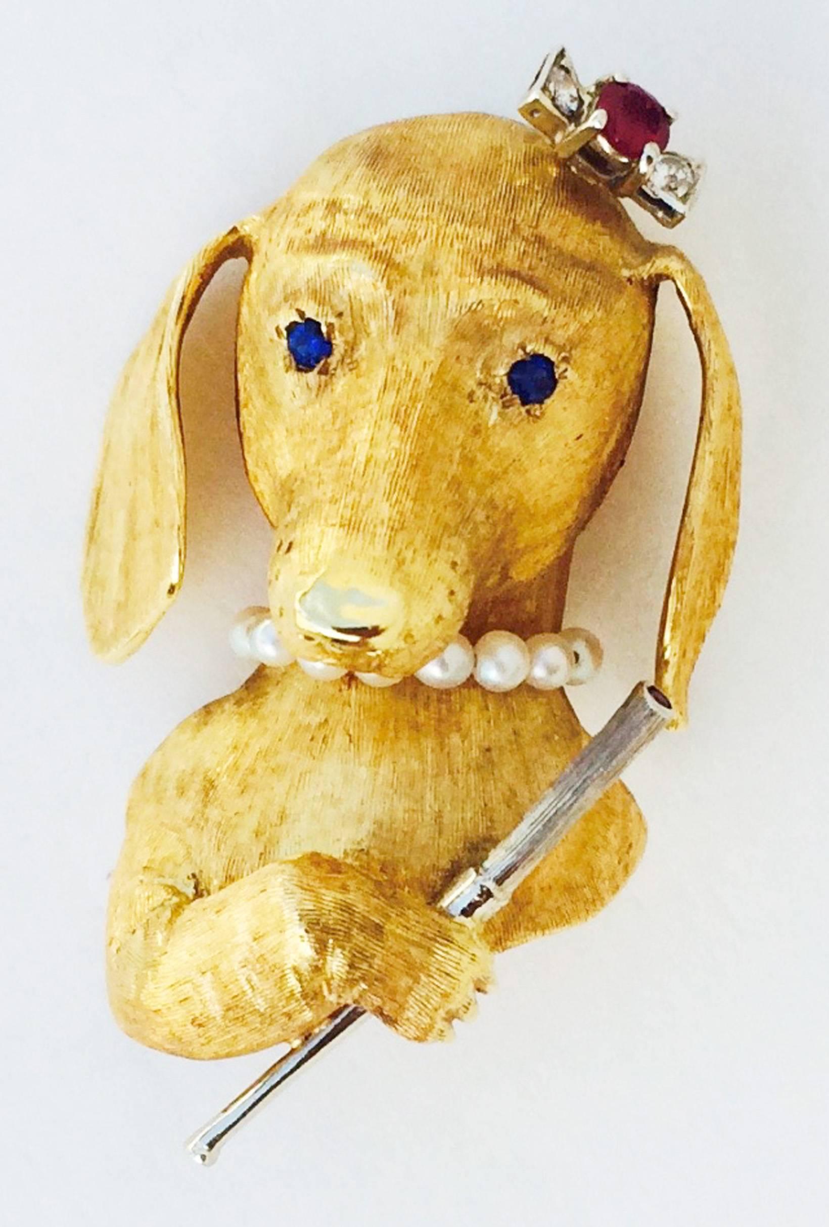 A charming mid-century jeweled hound dog brooch. Burnished two-tone yellow and white gold item depicts a smoking hound with sapphire 