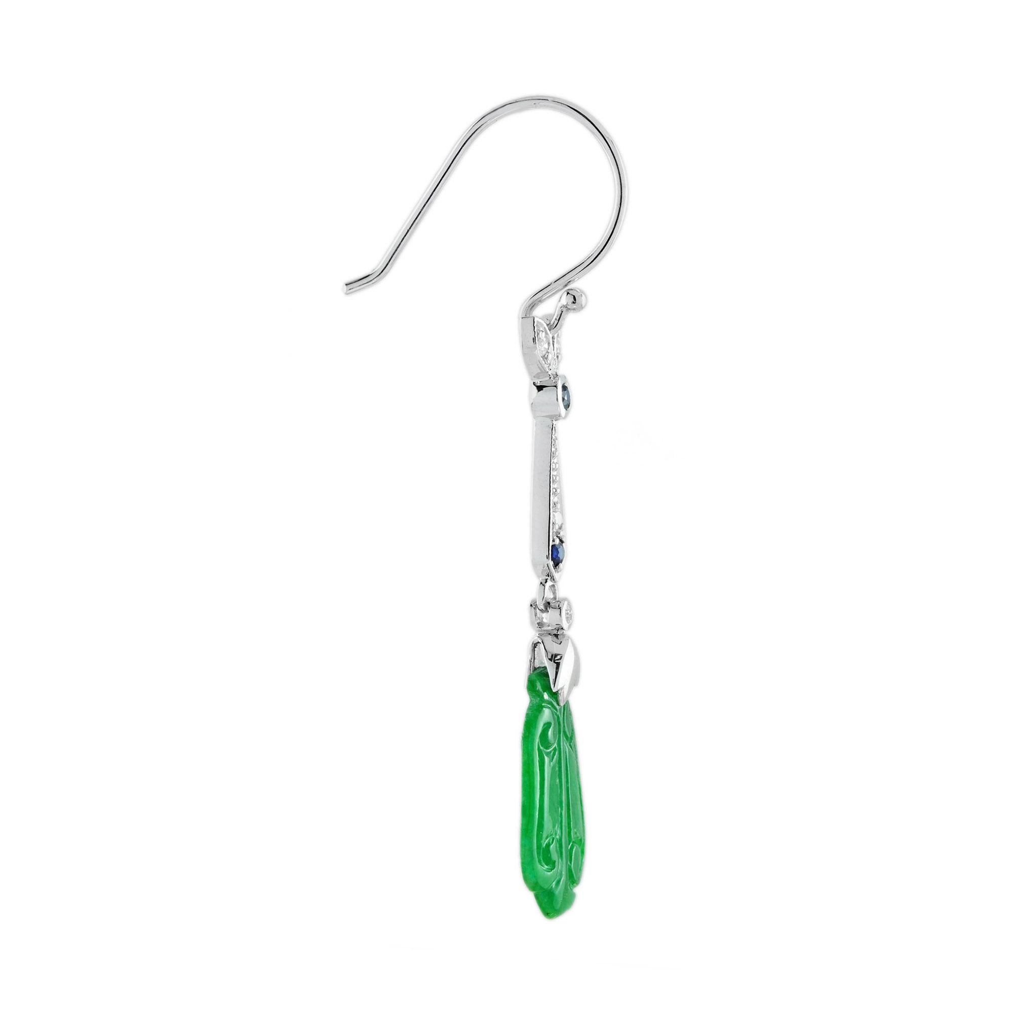 Die natürliche Jade in diesen schönen Ohrringen hat eine ganz besondere Form. Beide Stücke haben eine kräftige grüne Farbe und gute Schnitzereien. Die Jade hängt in einer Fassung aus 9 Karat Weißgold mit einem Diamantblatt und runden blauen Saphiren