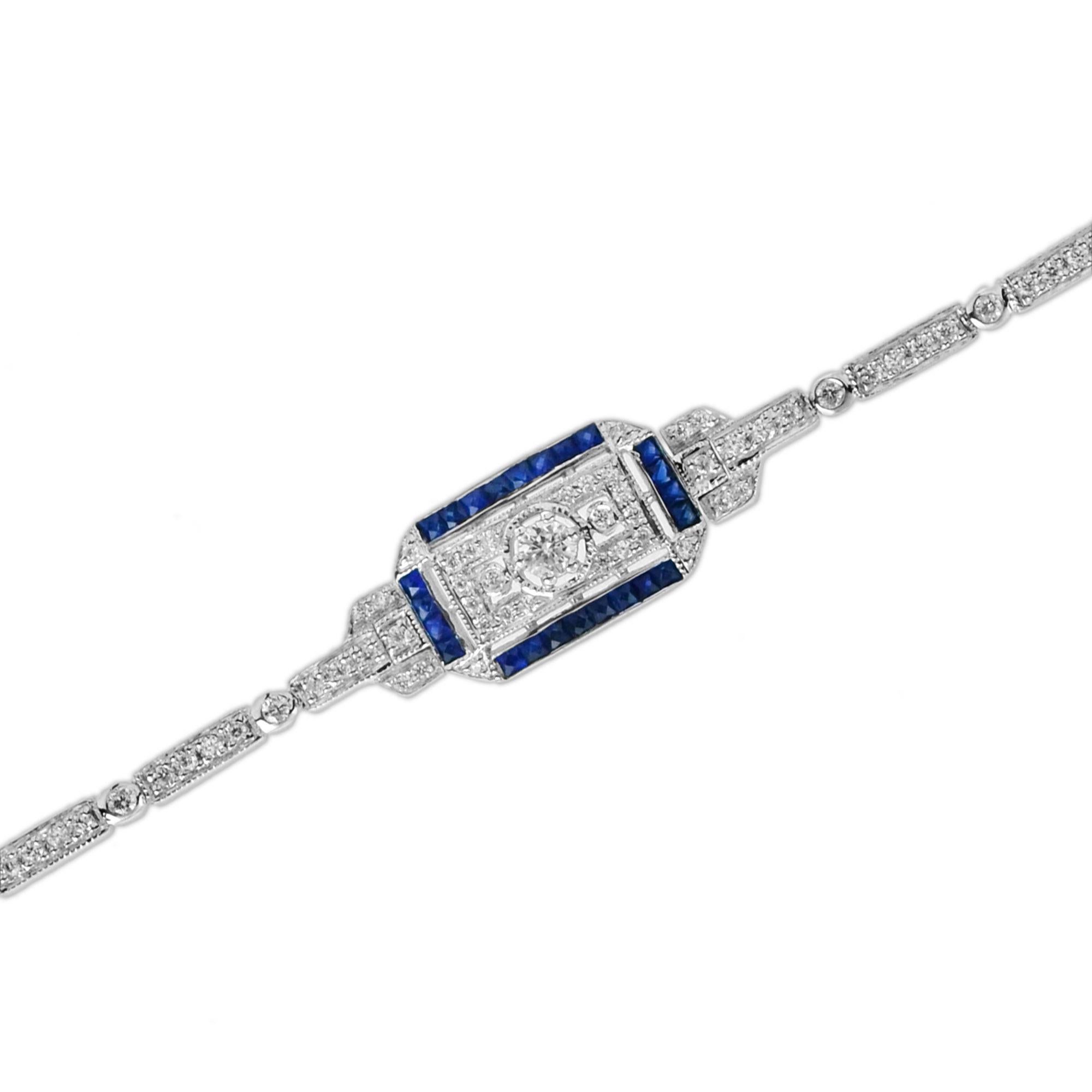 White Gold Art Deco bracelet with a center piece featuring a round cut diamond with a round brilliant cut to either side grain set to the borders with smaller round brilliant cuts and to the French cut blue sapphires frame. The shoulders and the