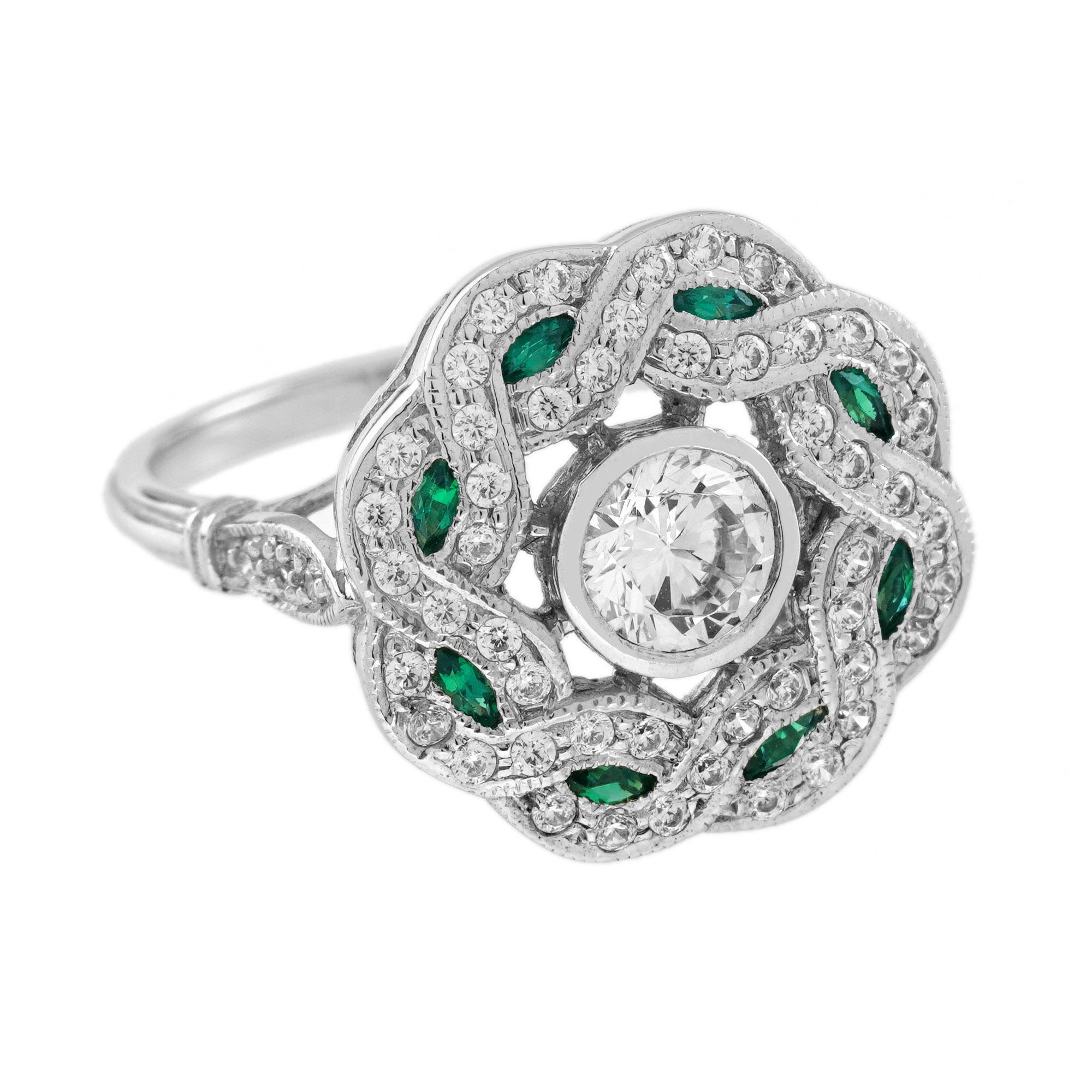 Questo anello con diamanti e smeraldi in stile Art Déco è assolutamente divino. È realizzato in oro bianco 18 carati e ha al centro un diamante rotondo taglio brillante da 0,5 carati, incastonato in un delizioso contorno traforato con smeraldi e