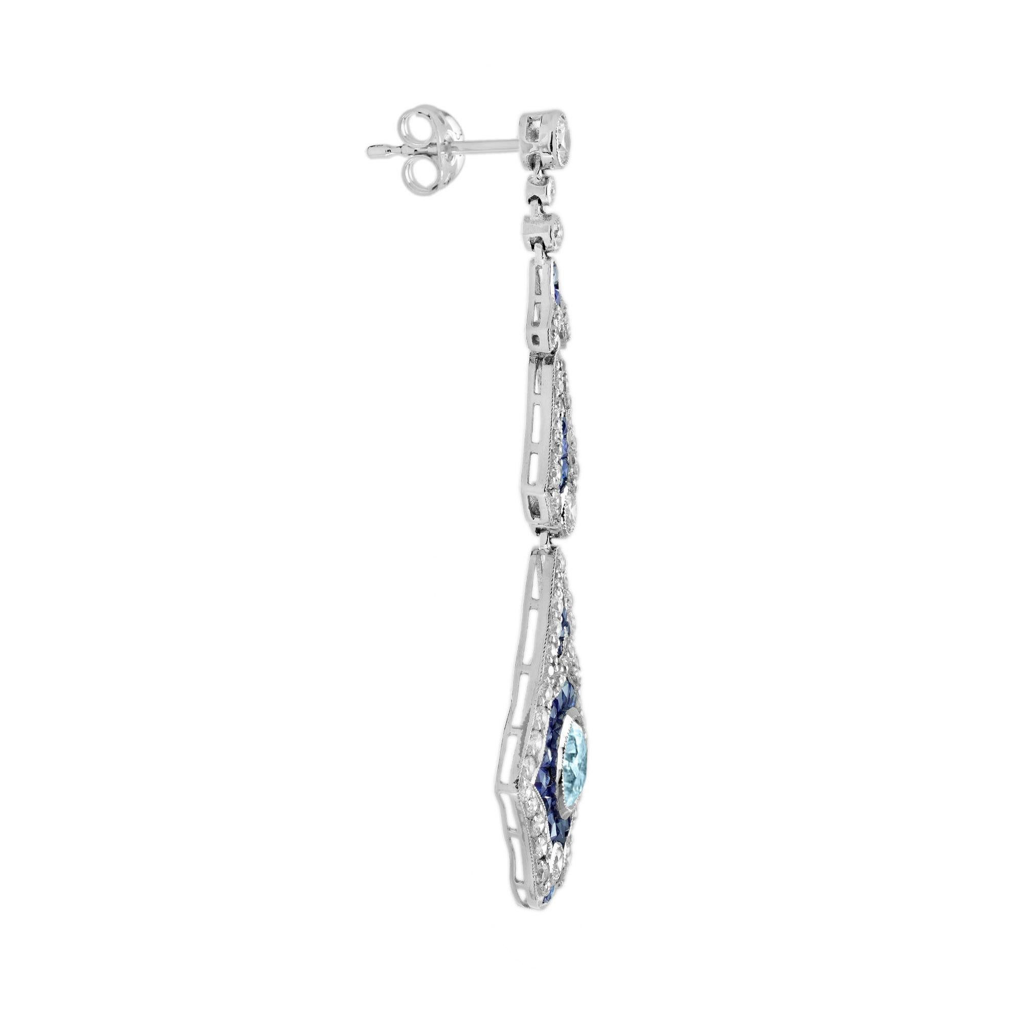 Une fabuleuse paire de boucles d'oreilles d'inspiration Art Déco, ornées d'aigues-marines rondes en leur centre, rehaussées de saphirs bleus de taille française et de diamants étincelants. Mesurant environ 56 mm. Ces boucles d'oreilles en forme de