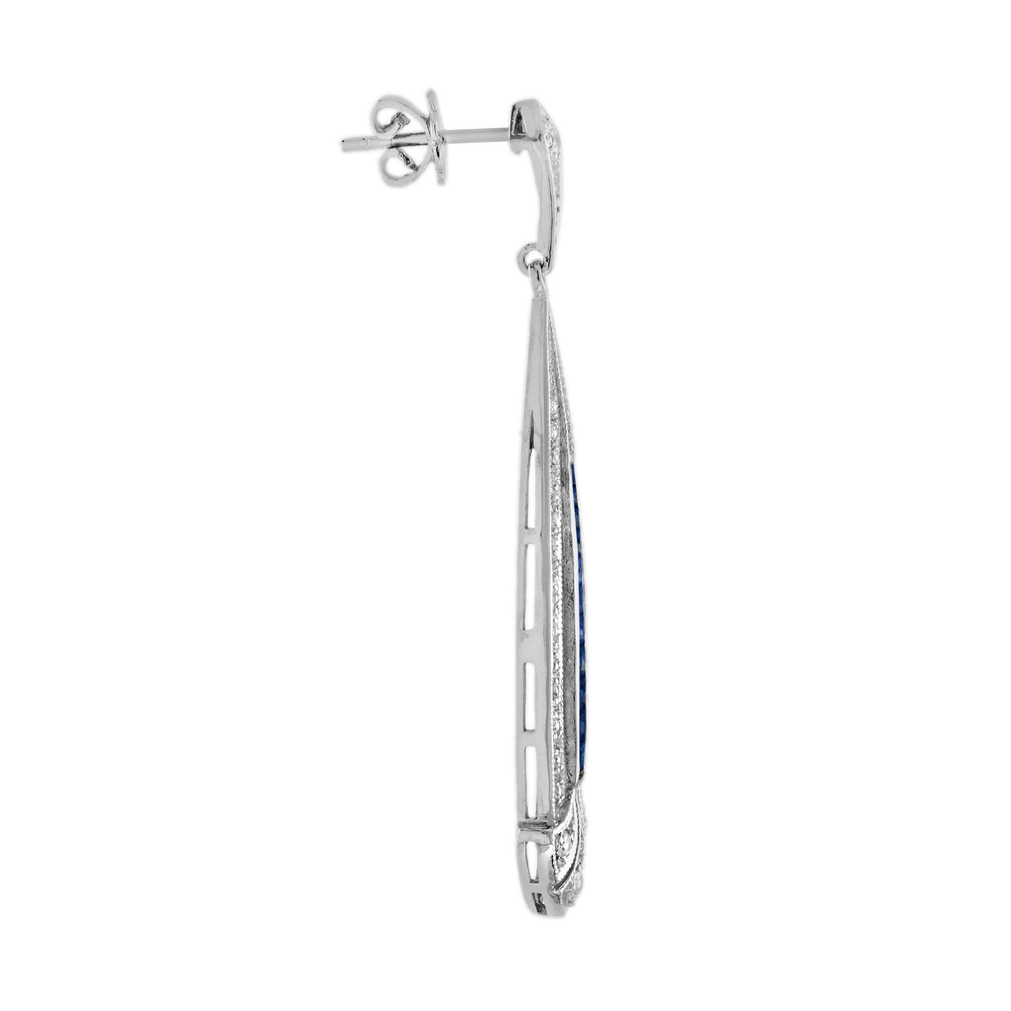 Une fabuleuse paire de boucles d'oreilles en saphir bleu et diamant d'inspiration Art Déco. Ces magnifiques boucles d'oreilles sont composées d'un long saphir bleu de taille française et d'un diamant en forme de flèche, suspendus à un diamant rond