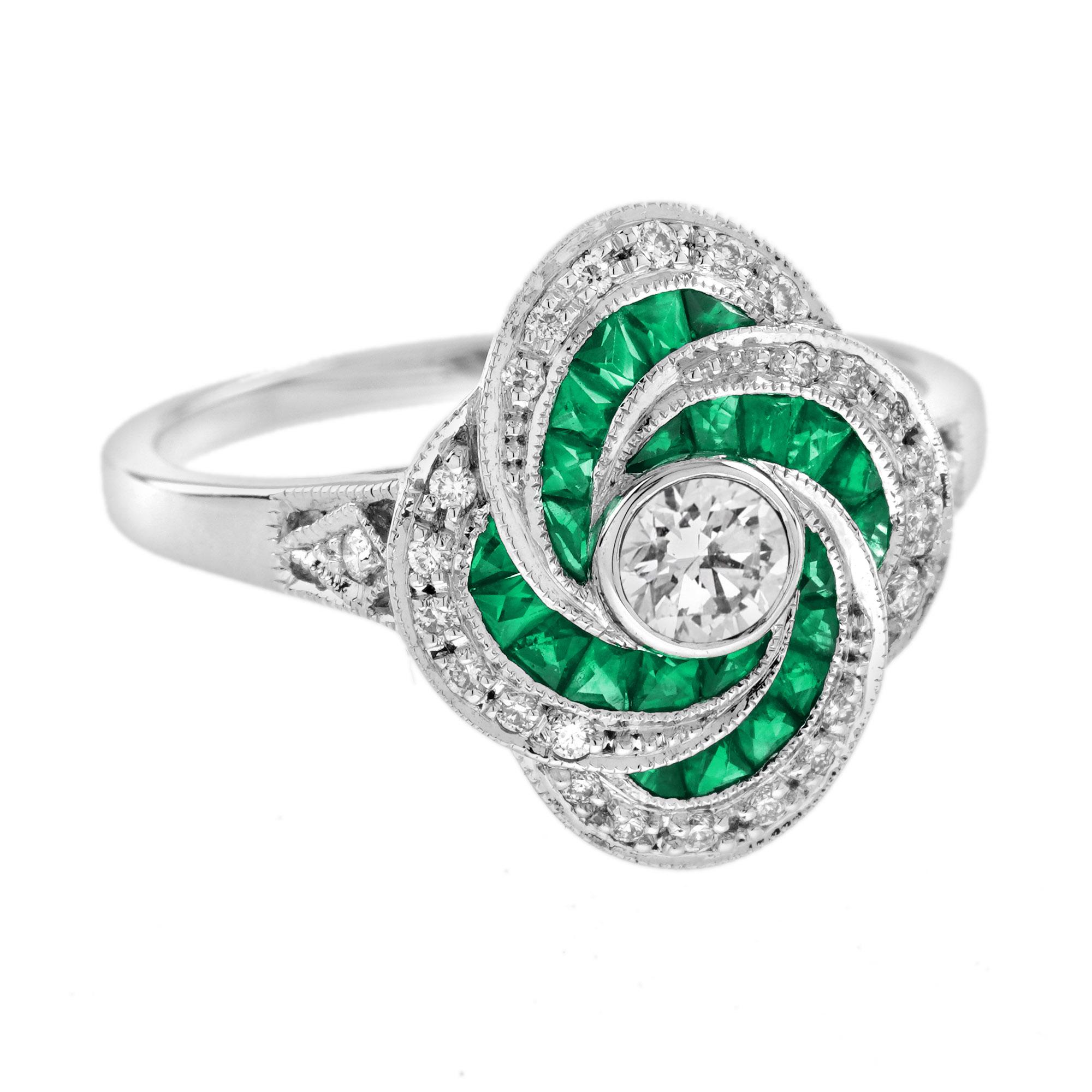 Ein faszinierendes Ensemble aus Diamant und Smaragd, ein wirbelnder Verlobungsring. Dieses vom Art Deco inspirierte, handgefertigte Meisterwerk hat als Mittelpunkt einen runden Diamanten von ca. 0,25 Karat, der von Smaragden und Diamanten im