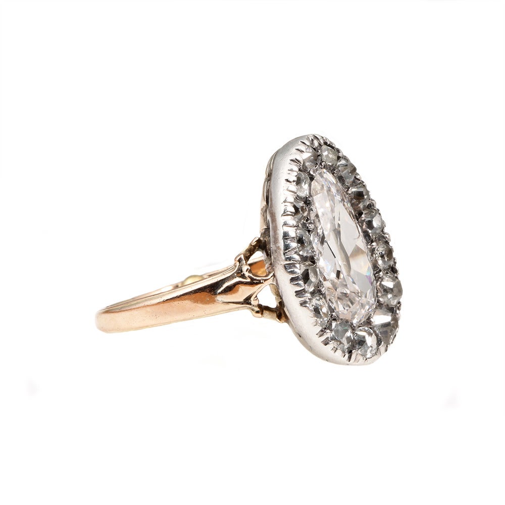 Victorian Era Pear Shaped Diamond Ring in silver on gold setting, Circa 1890. Central old mine pear shaped stone surrounded by 15 old mine cut diamonds in graduated sizes.

Size 5.75, can be sized. The shank has two old sizing beads on the