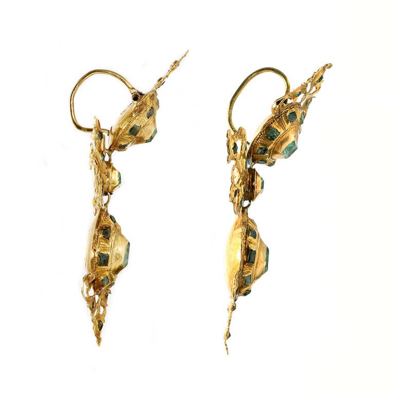 Circa 1780, these earrings are Spanish in origin.  Hand made in 18k gold and emeralds, most probably sourced in colonial mines in Columbia and Peru. Original ear wires and in Lazo earrings, the Spanish word for bow, they are a variation on the