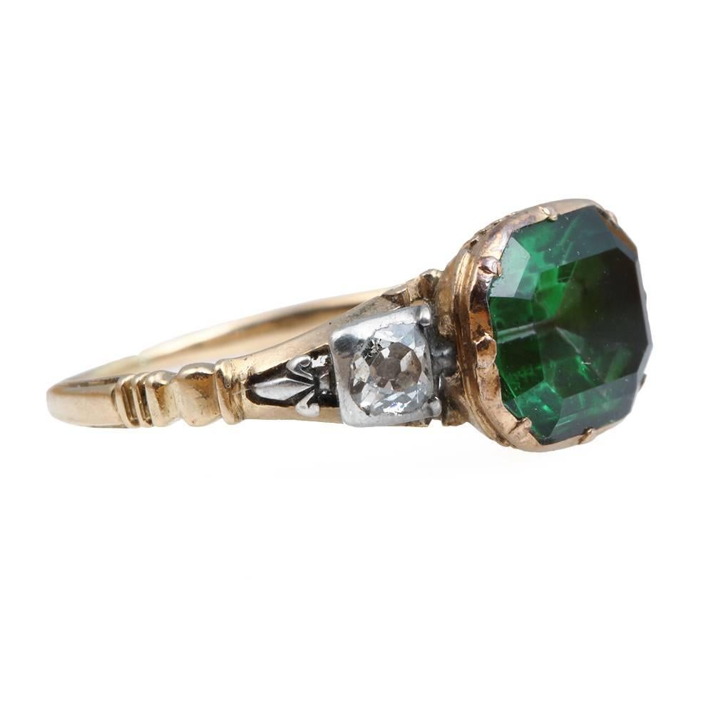 Georgian three stone ring with central simulated emerald in painted rock crystal with two old mine cut diamonds. Diamonds are set in silver while the rock crystal is set in gold on a gold band. The reeded back detail indicates the year of