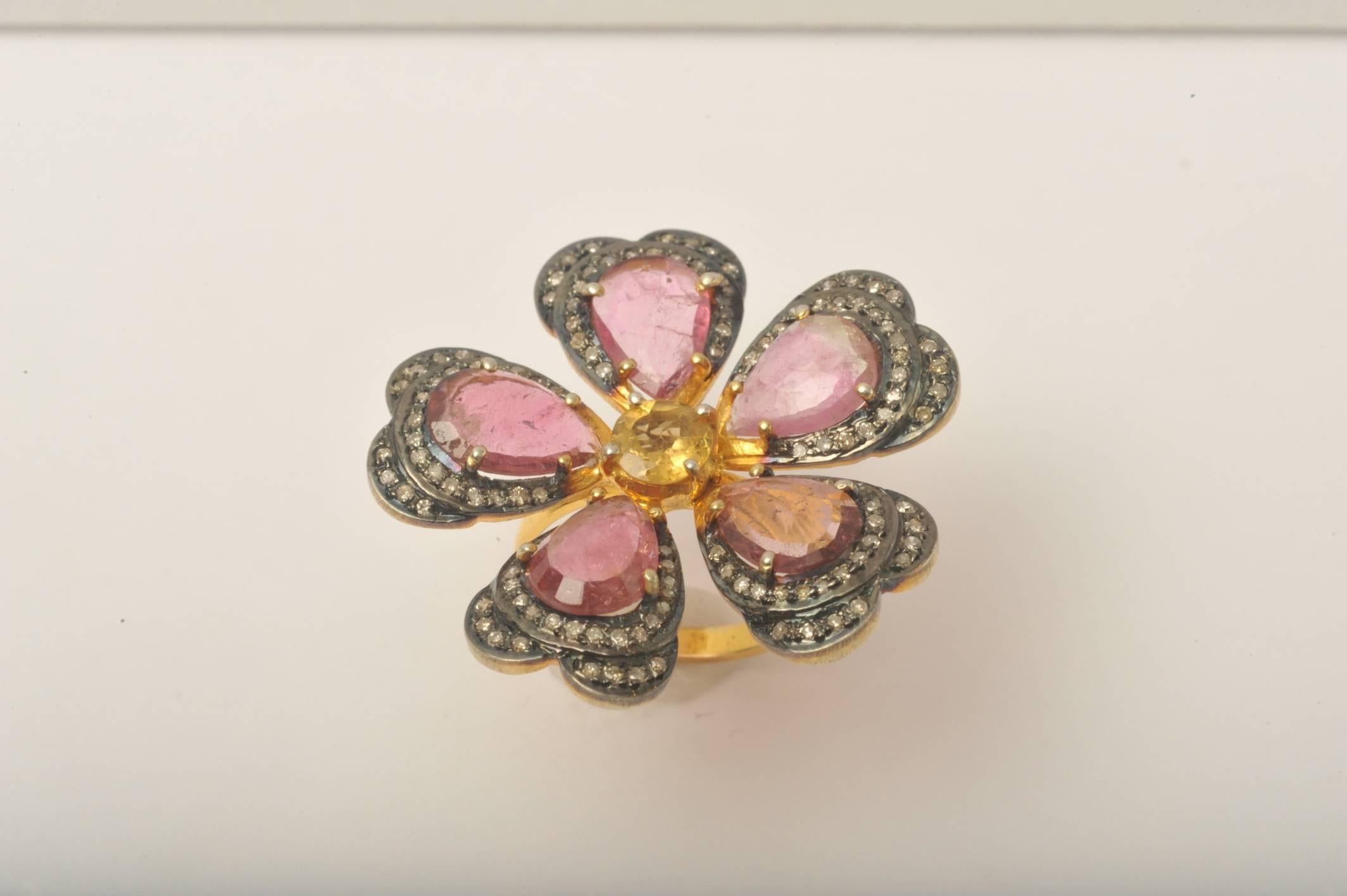 A stunning flower ring of pear-shaped, faceted pink tourmalines bordered with pave`set diamonds set in oxidized sterling.  At the center is a faceted yellow tourmaline bordered in vermeil, as is the band.

Carat weight for tourmalines is